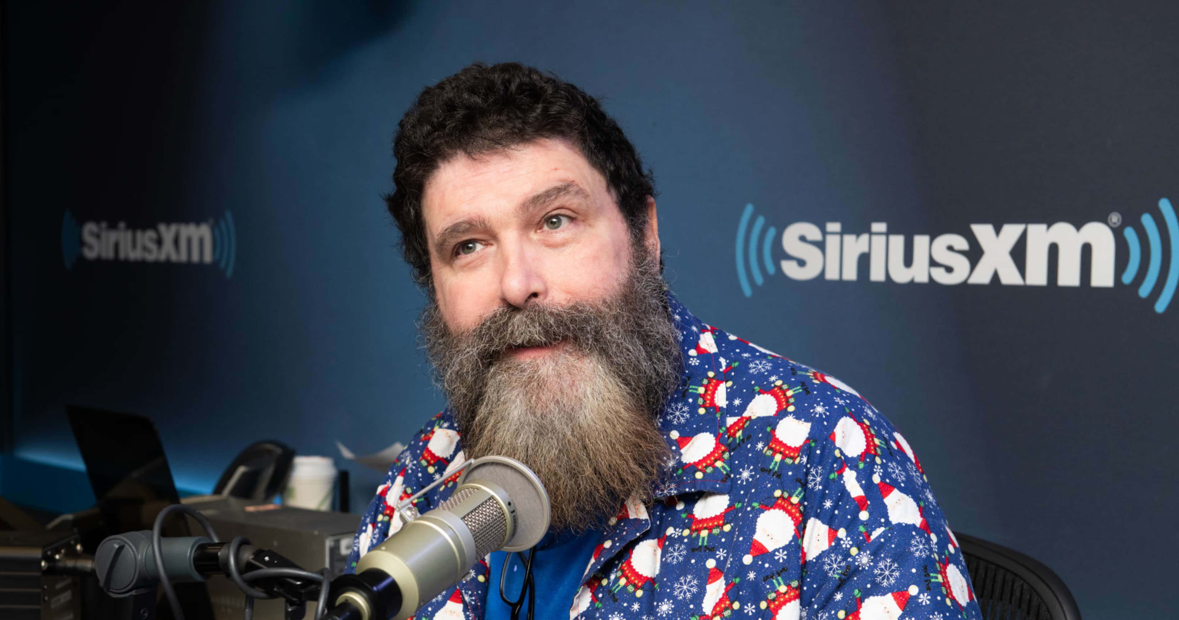 WWE 桌布 壁紙 — 一位留鬍鬚的男子穿著節日聖誕主題襯衫，在SiriusXM錄音室對著麥克風說話。