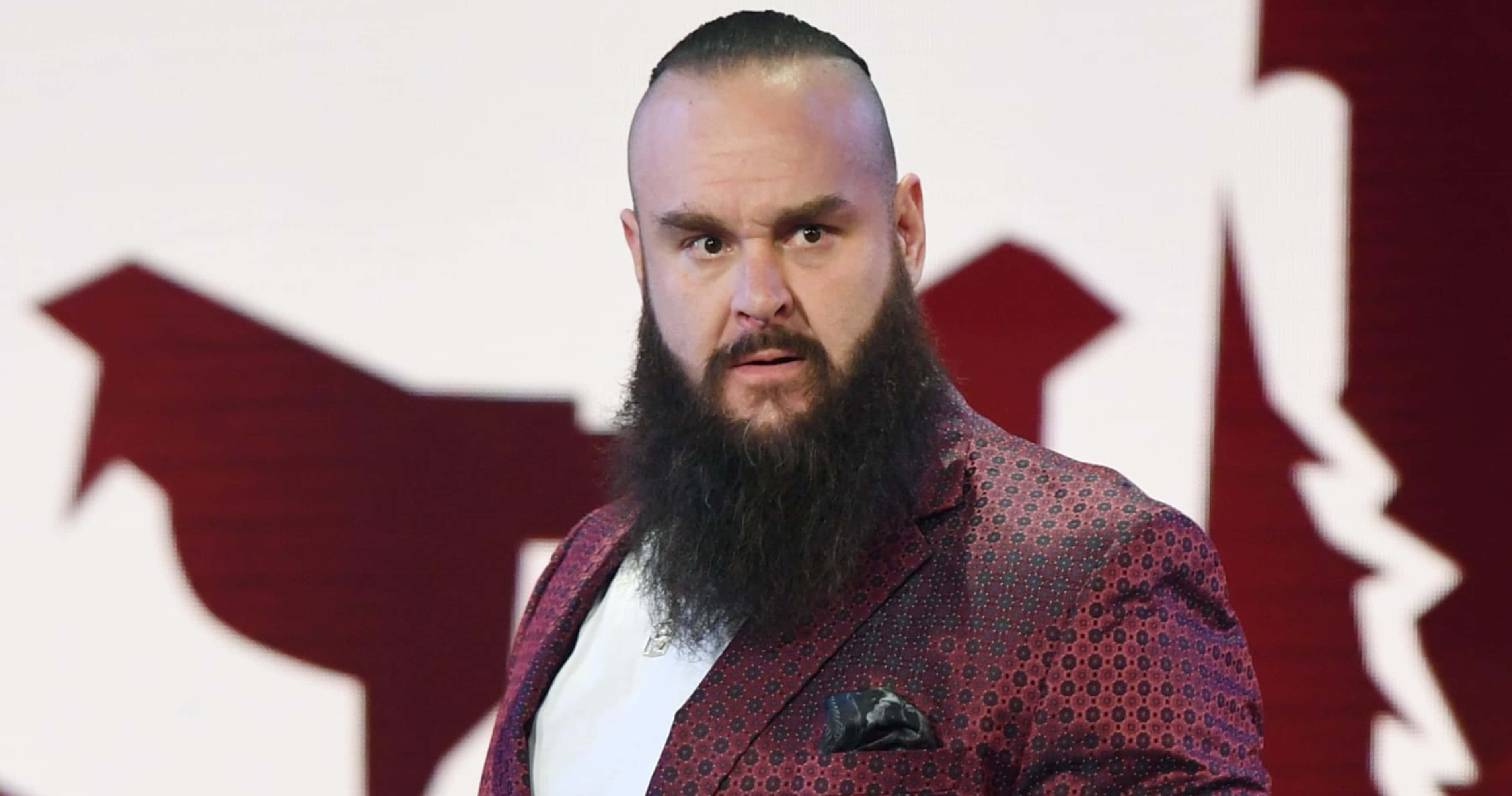 WWE 桌布 壁紙 — 一位留鬍鬚的男子身穿圖案酒紅色西裝外套，站在大膽的紅白圖形背景前。