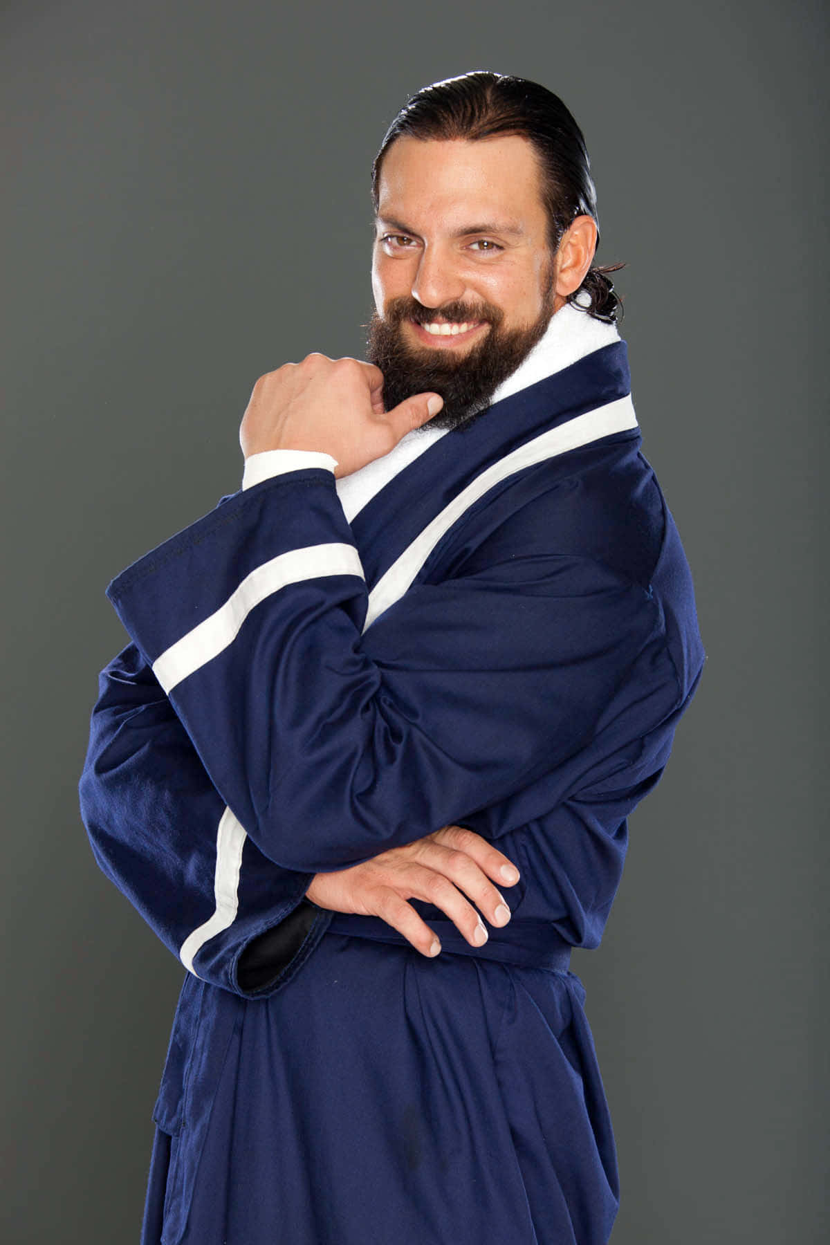WWE 桌布 壁紙 — 一位留鬍鬚的男子身穿帶有白色條紋的海軍藍長袍，在灰色攝影棚背景前自信地微笑擺姿勢。