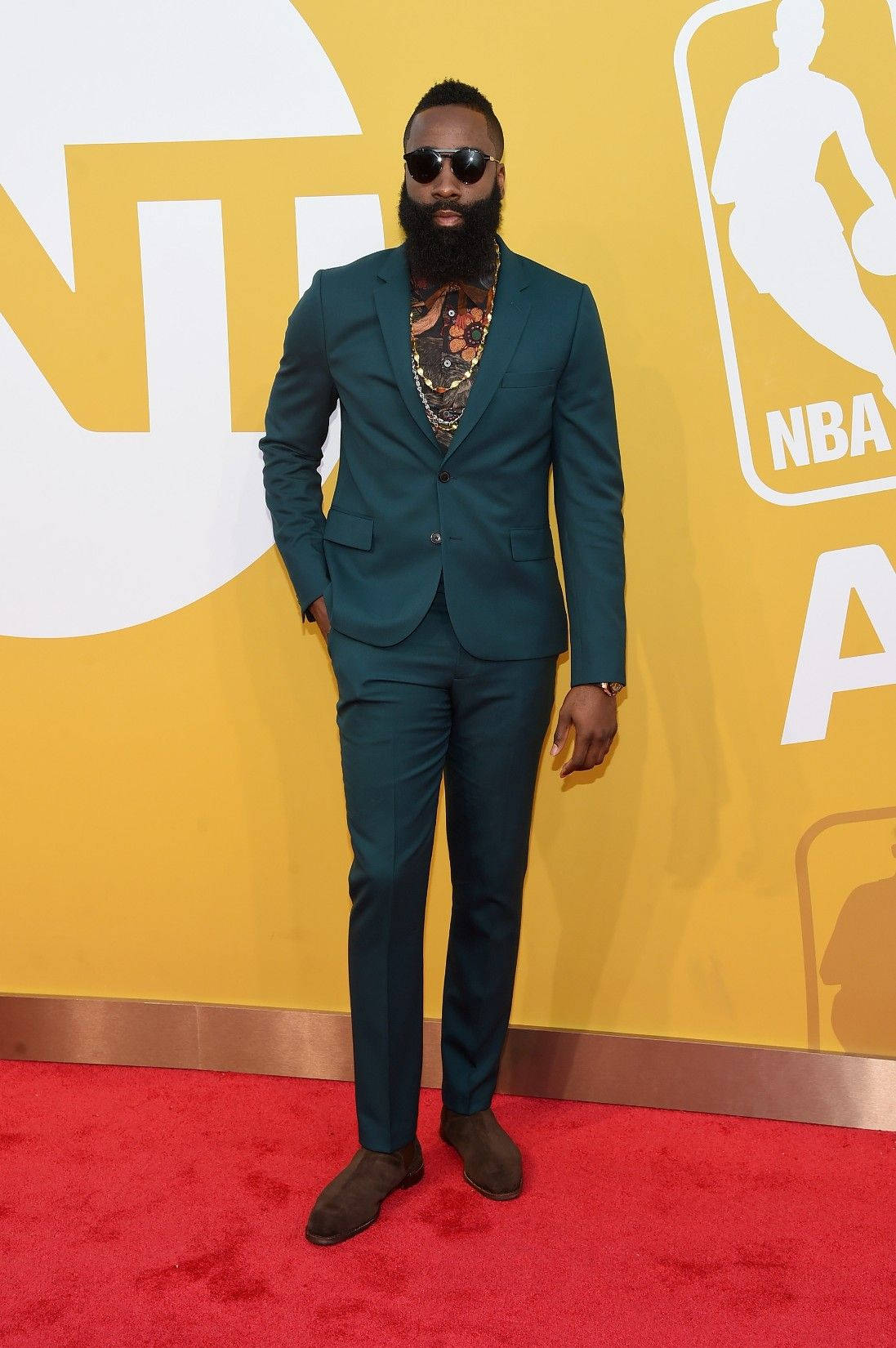 James Harden 桌布 壁紙 — 一位留鬍鬚的男子身穿青綠色西裝和太陽眼鏡，自信地站在紅地毯上，背景是黃色的NBA Awards背景。
