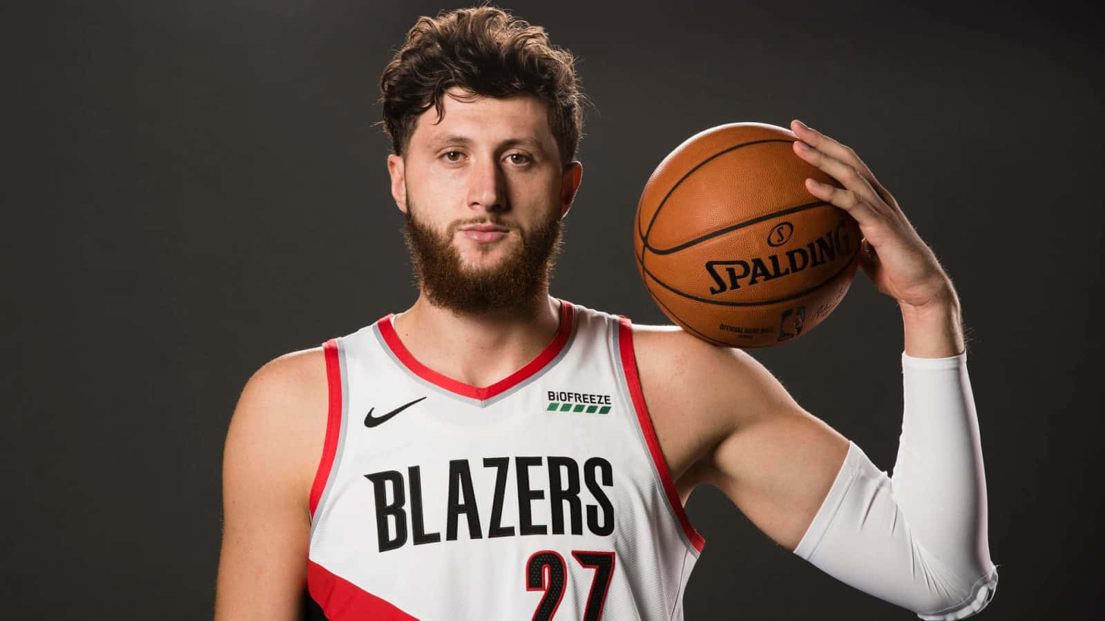 籃球 桌布 壁紙 — 一位留鬍鬚的籃球運動員身穿白色Blazers球衣，在深色工作室背景下拿著Spalding籃球。
