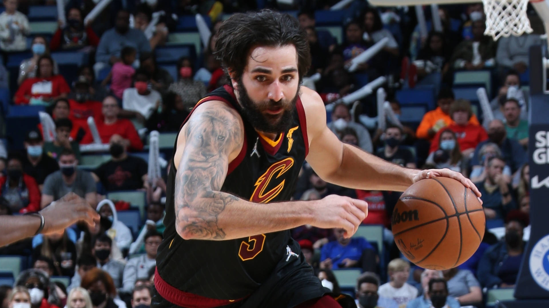 Ricky Rubio 桌布 壁紙 — 一位留鬍鬚的籃球運動員身穿黑色球衣，在比賽中激烈運球，觀眾在旁觀看。
