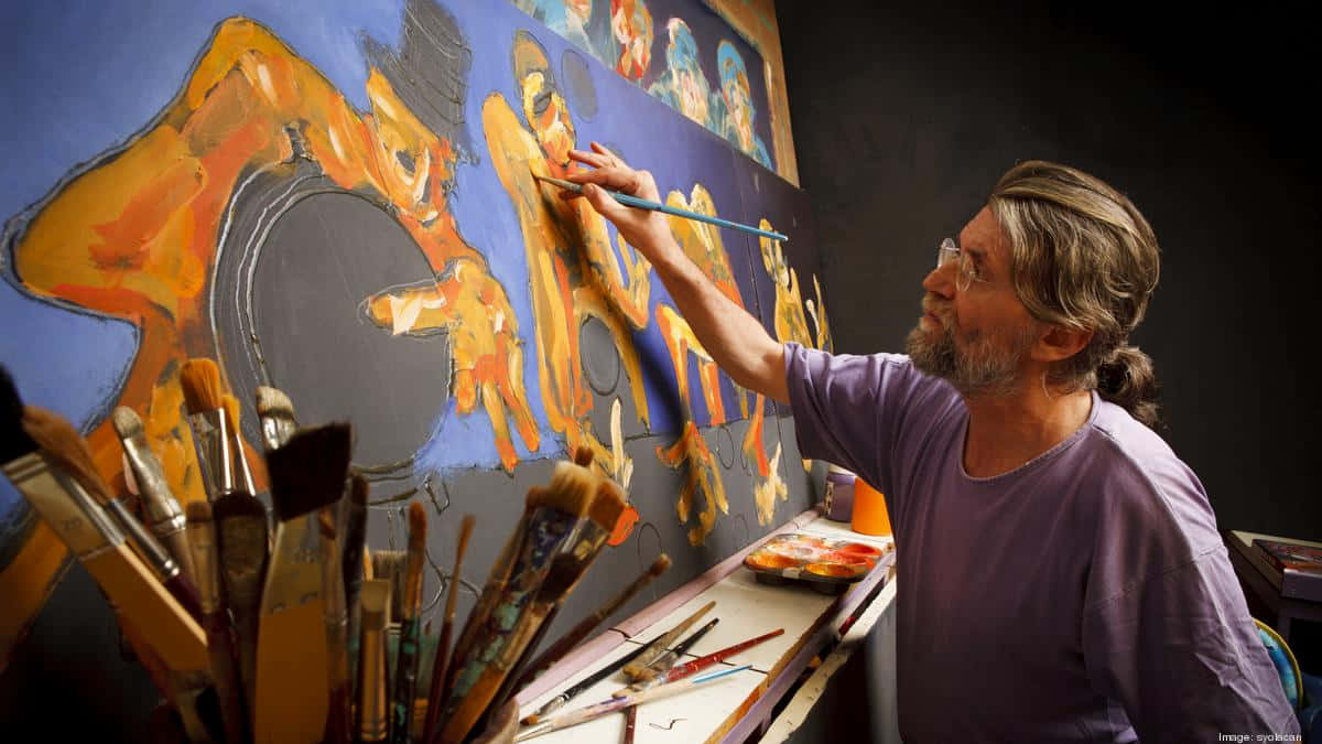 Painting 桌布 壁紙 — 一位留鬍鬚的藝術家穿著紫色襯衫，在燈光昏暗的工作室裡熱情地繪製一幅帶有橙色和藍色筆觸的大型抽象壁畫。