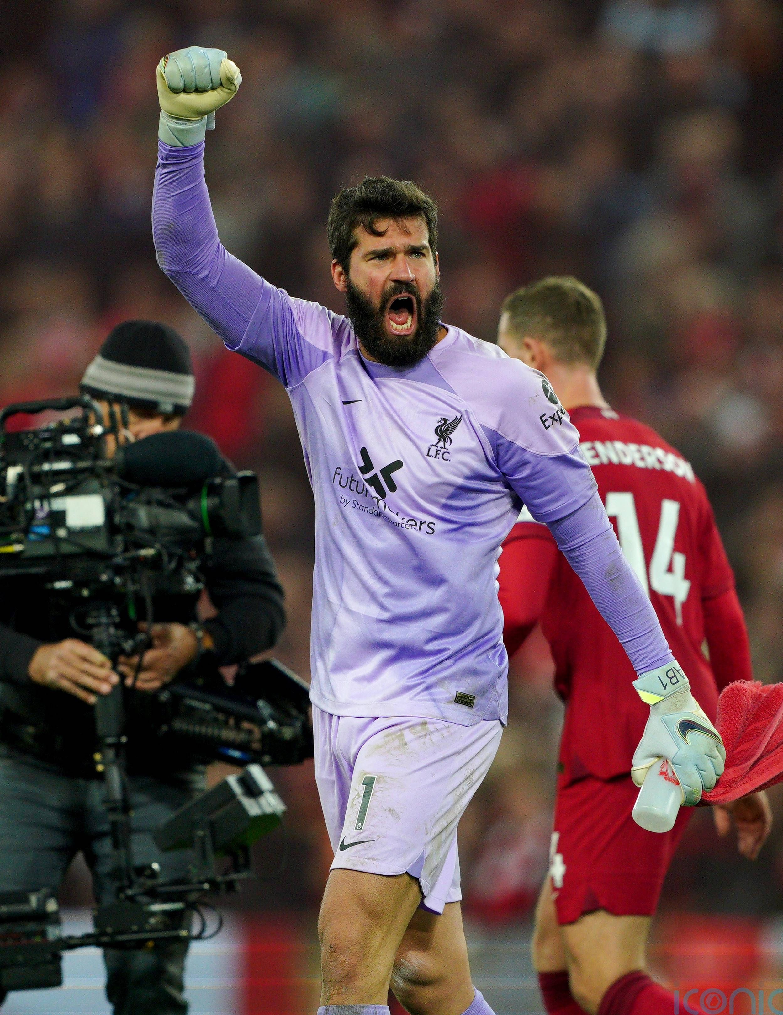 Alisson Becker 桌布 壁紙 — 一位留鬍鬚的足球守門員身穿紫色球衣，在比賽中高舉拳頭，發出勝利的吼叫。