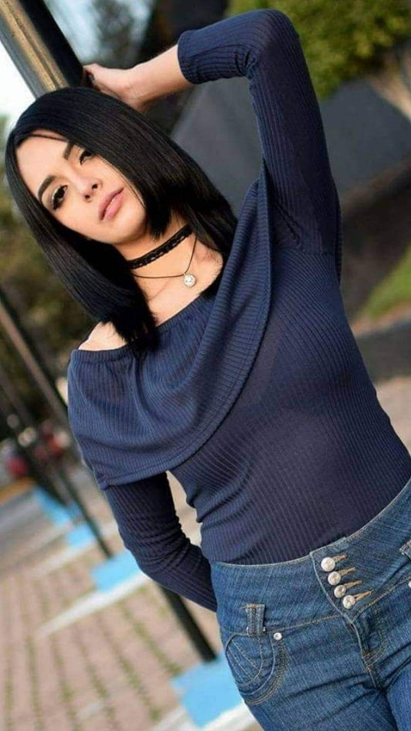 Mexican 桌布 壁紙 — 一位留黑色鮑伯頭的年輕女子靠在柱子上，身穿海軍藍羅紋上衣和藍色牛仔褲。