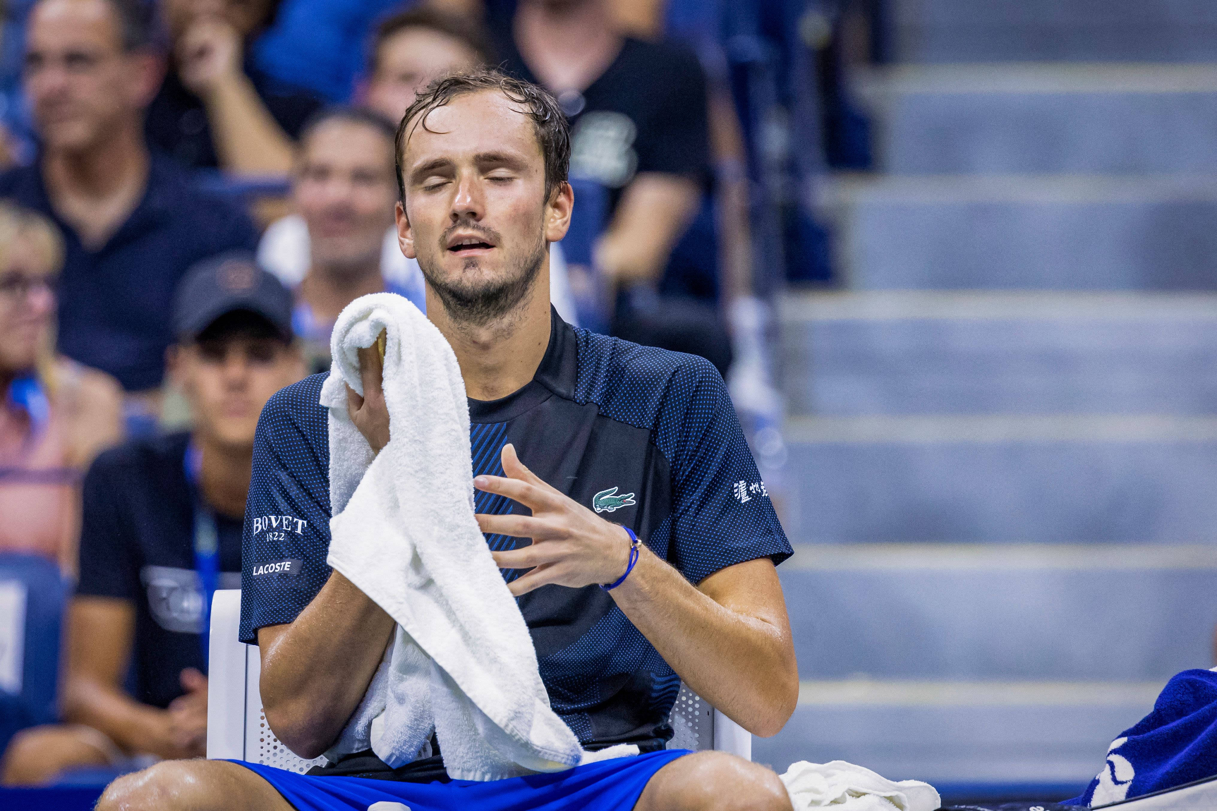Tennis 桌布 壁紙 — 一位疲憊的網球選手在明亮的體育場燈光下，坐在長椅上用毛巾擦汗。