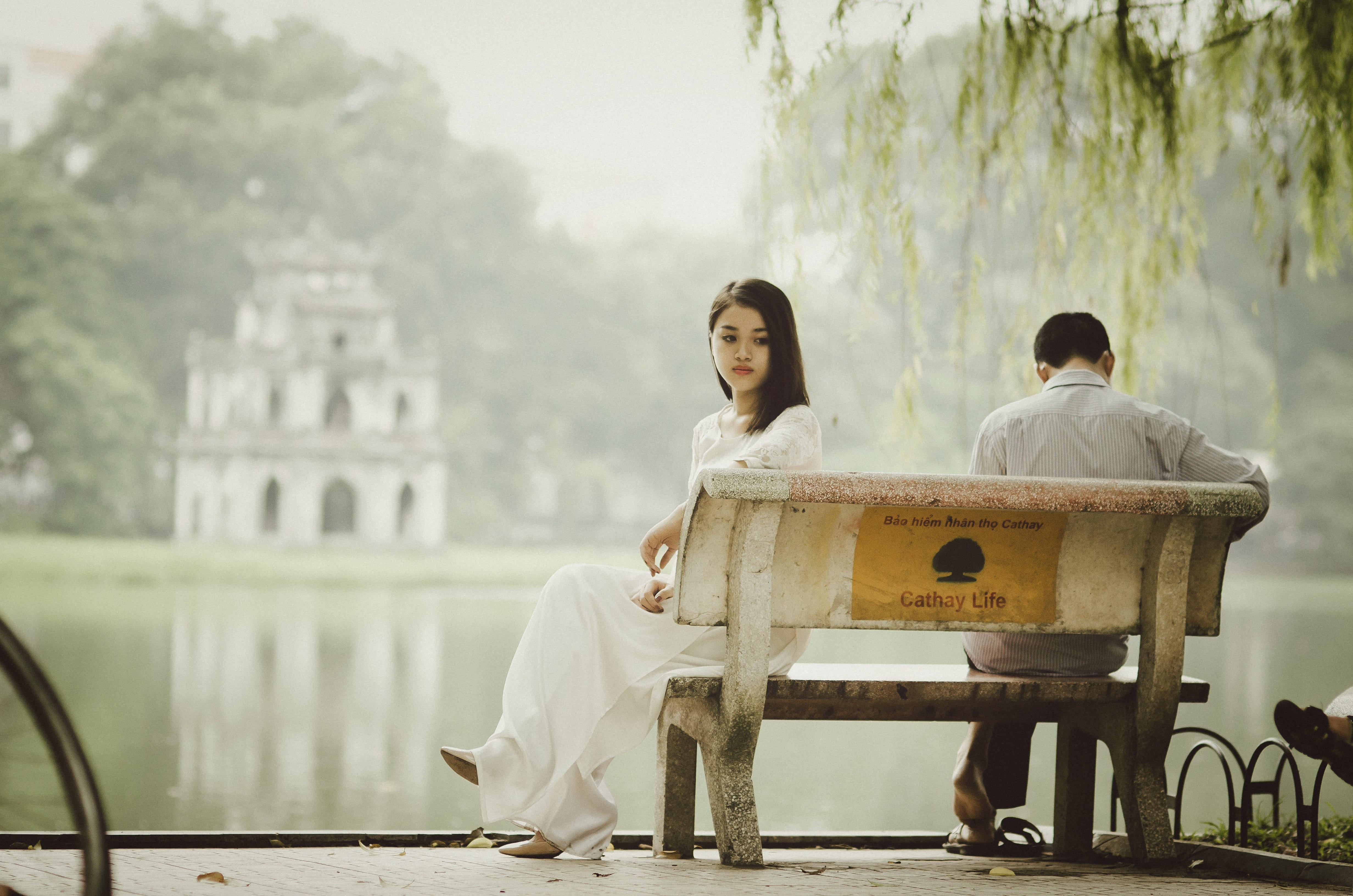 breakup 桌布 壁紙 — 一位白衣女子與一名男子面對面坐在湖邊一張經風雨侵蝕的長椅上，背景是柔焦的遠方寶塔。