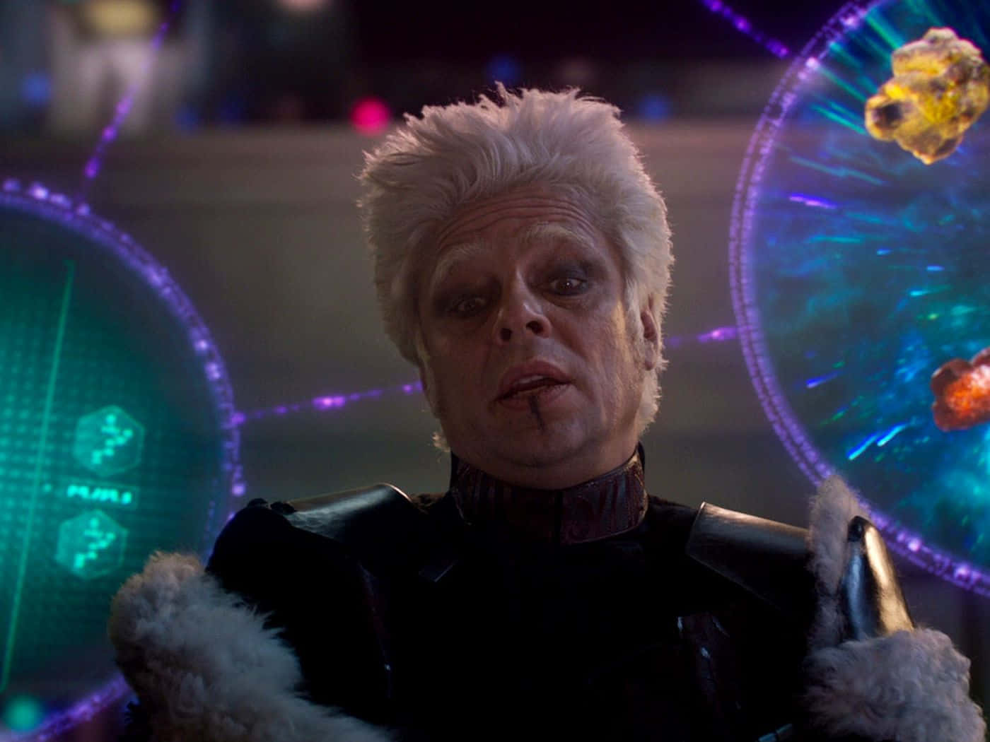 Mind Stone 桌布 壁紙 — 一位白髮、深色妝容的男子在科幻控制室中，對著發光的全息螢幕凝視。