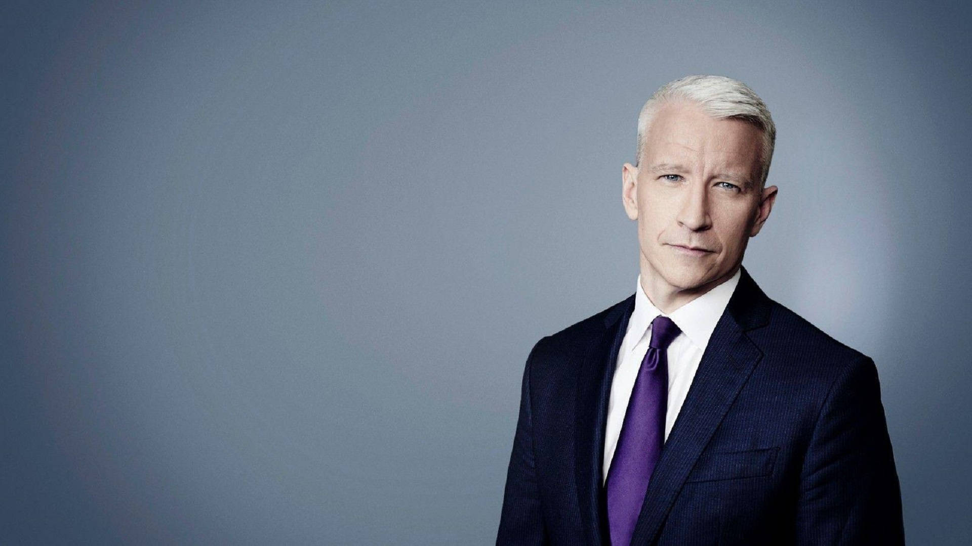 Cnn 桌布 壁紙 — 一位白髮男士穿著深色西裝和紫色領帶，背景是柔和的灰色攝影棚。