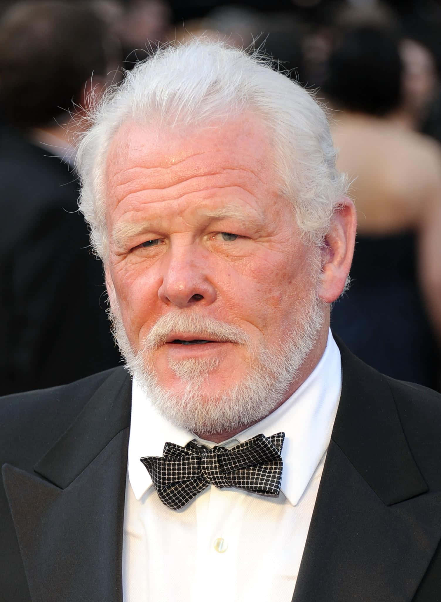 Nick Nolte 桌布 壁紙 — 一位白髮白鬍鬚的尊貴長者身穿黑色燕尾服和格紋領結的特寫肖像。