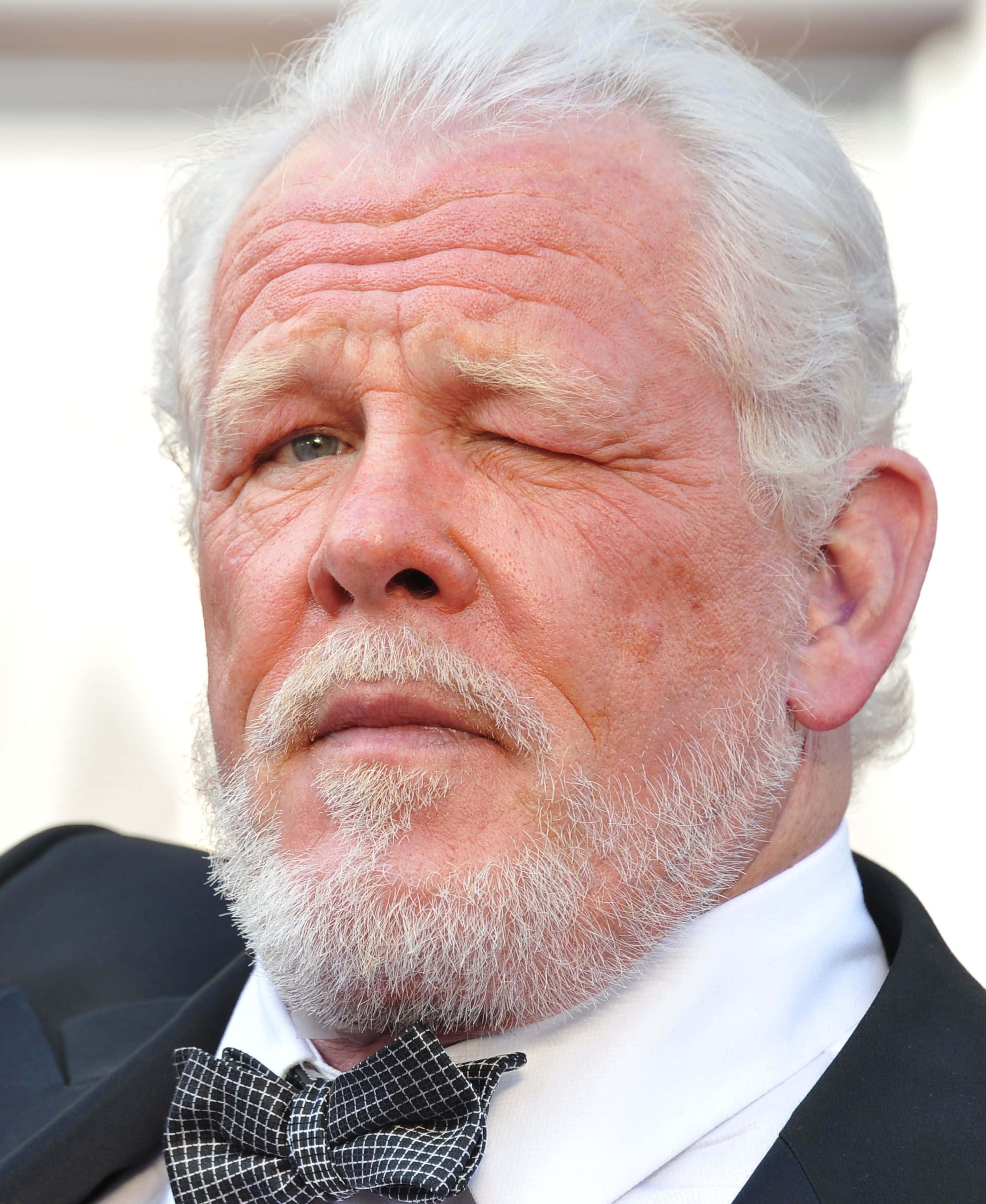 Nick Nolte 桌布 壁紙 — 一位白髮白鬚、飽經風霜的長者穿著禮服頑皮地眨眼特寫。