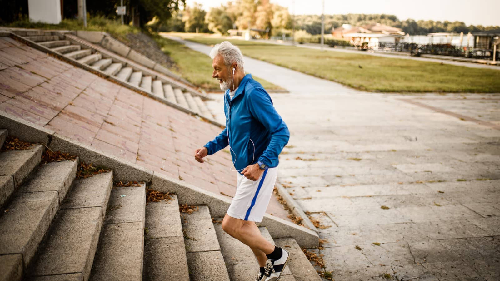 Running 桌布 壁紙 — 一位白髮老人在公園穿著藍色外套和白色短褲跑上石階。