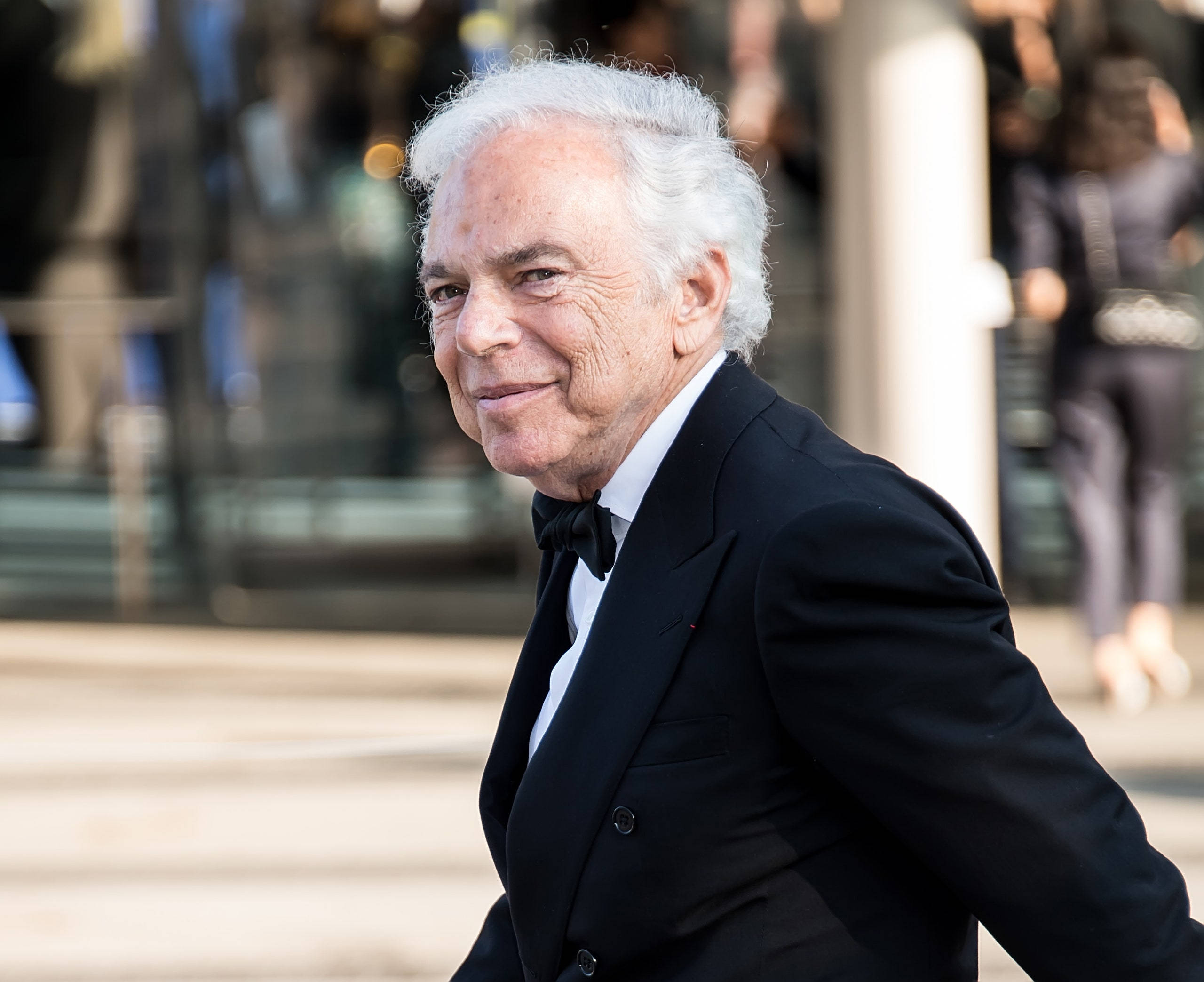 ralph lauren 桌布 壁紙 — 一位白髮老人在戶外穿著黑色禮服和領結，溫暖地微笑。