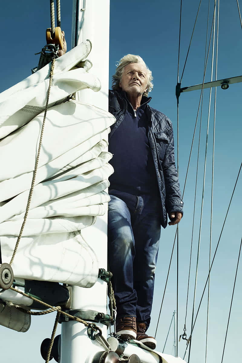 actor 桌布 壁紙 — 一位白髮老翁自信地站在帆船的桅杆上，背景是清澈的藍天。