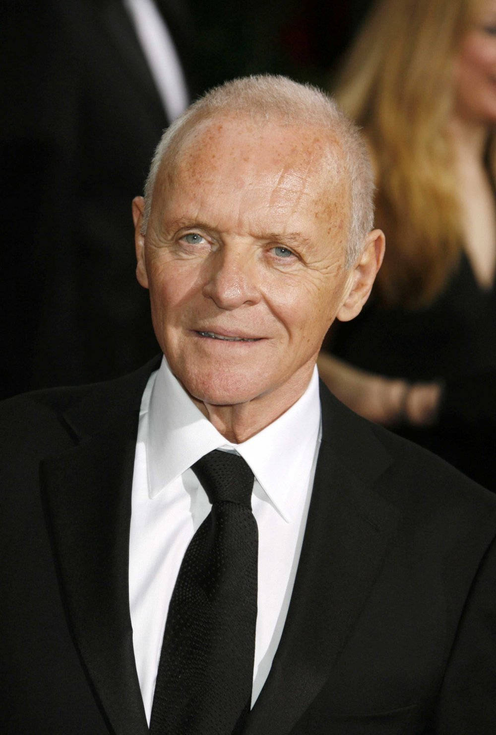 actor 桌布 壁紙 — 一位白髮藍眼的年長男士在正式活動中穿著黑色西裝打領帶，露出溫暖的笑容。