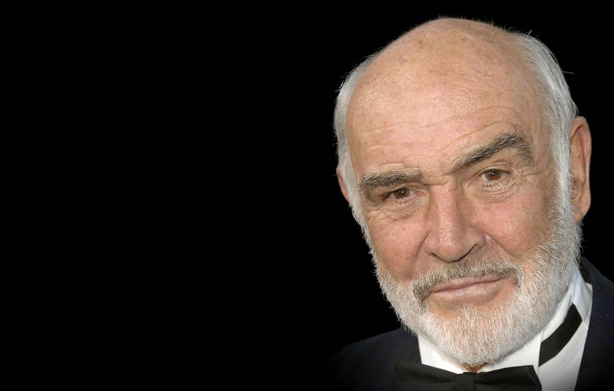 Sean Connery 桌布 壁紙 — 一位白鬍鬚、目光銳利的高貴長者特寫肖像，背景為純黑色。