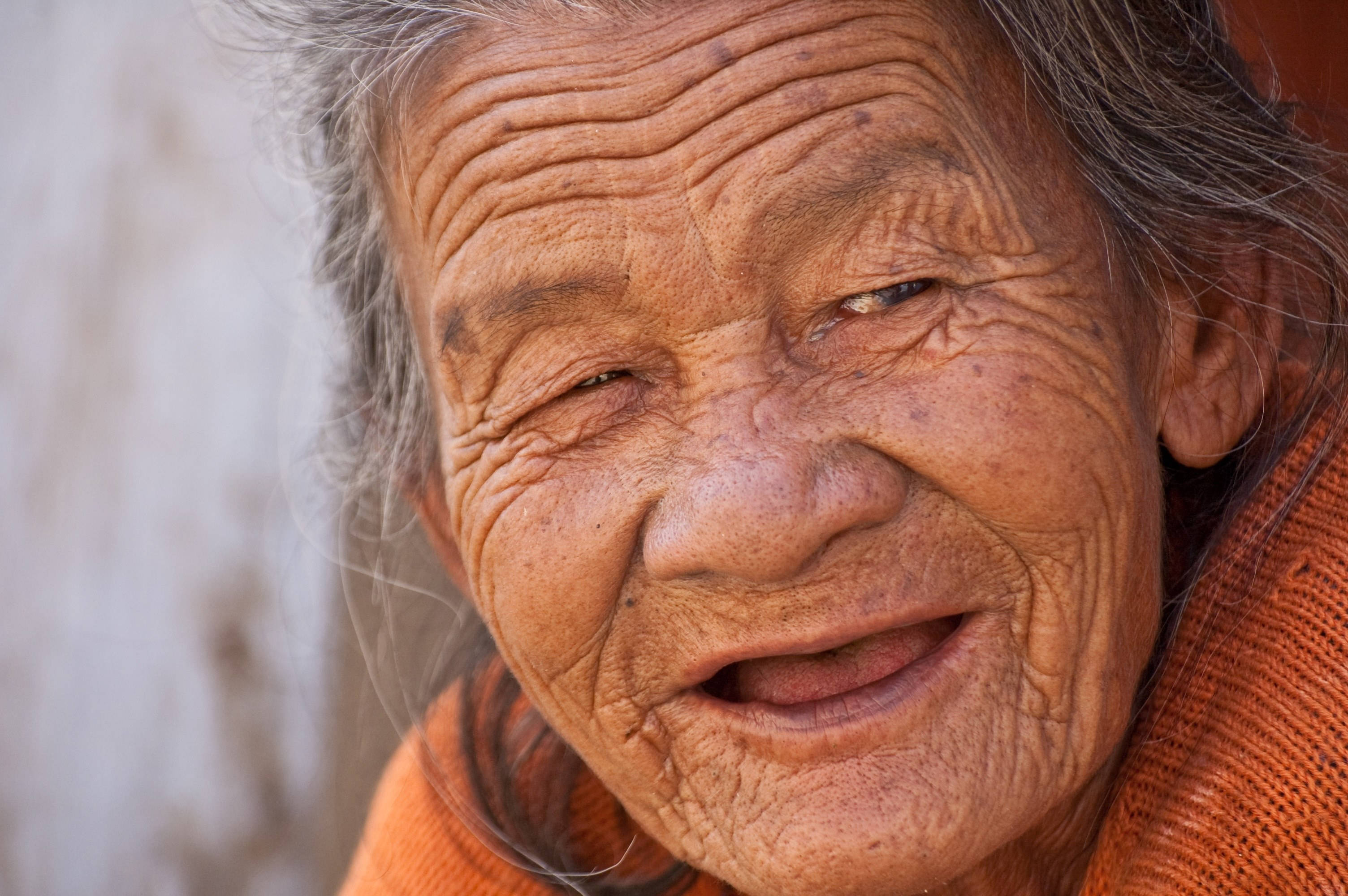 smiling 桌布 壁紙 — 一位皮膚深皺的老婦人在柔和自然光下溫暖微笑的特寫。
