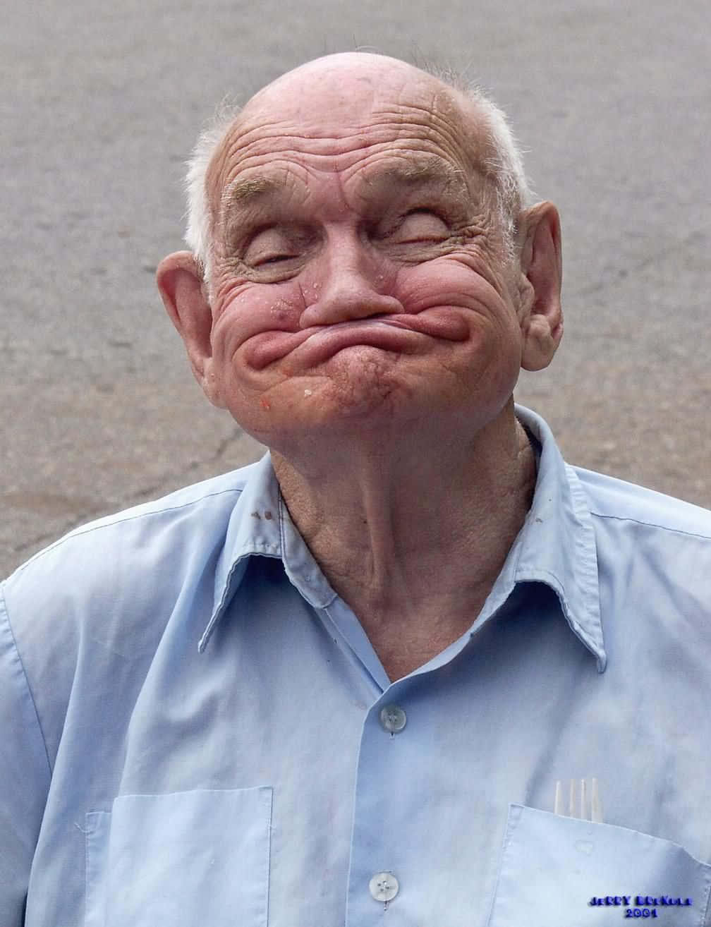 meme 桌布 壁紙 — 一位皮膚皺紋、白髮的老年男子在純灰色背景前做鬼臉。
