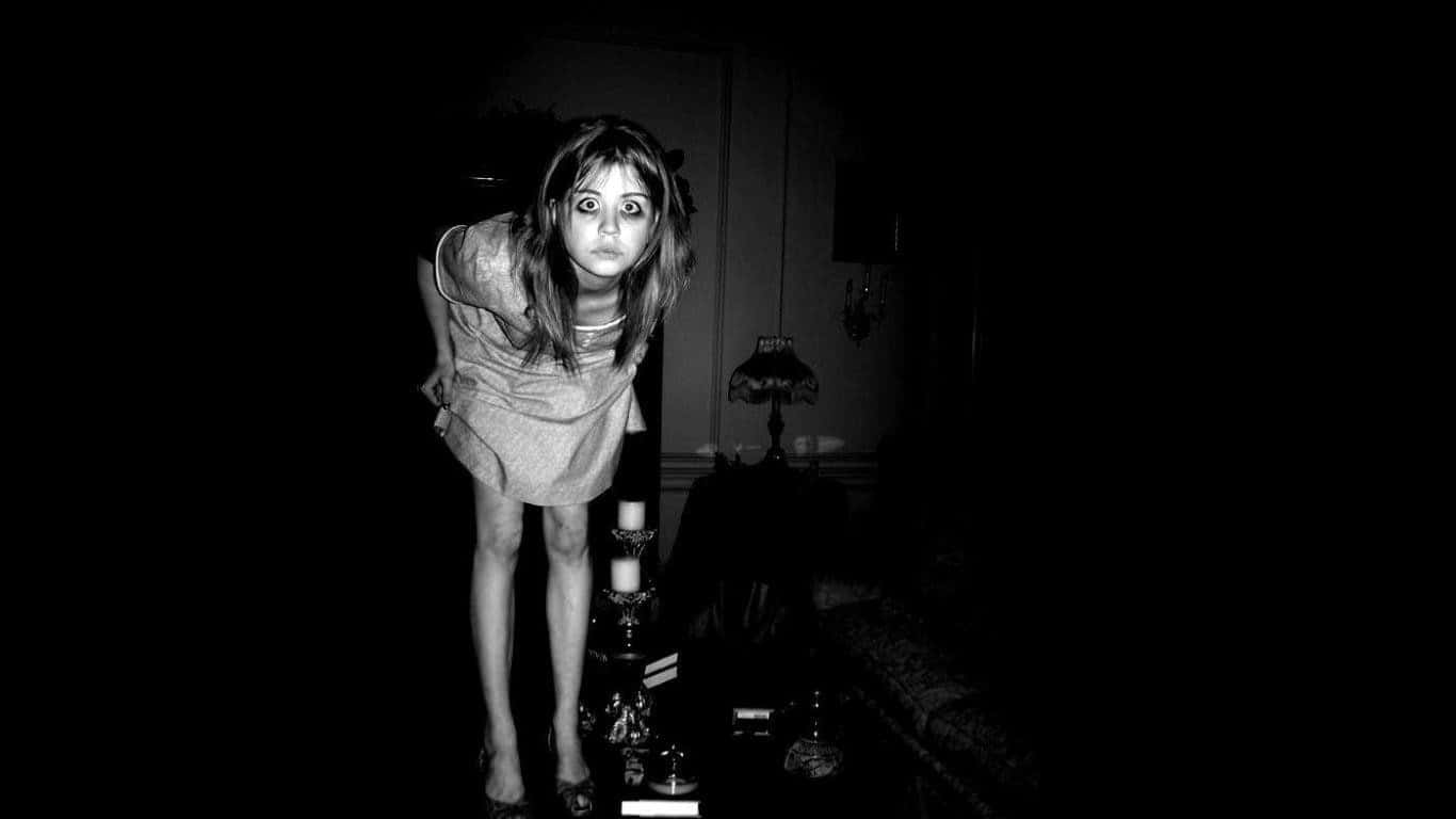 Dark Fear 桌布 壁紙 — 一位眼睛睜大的女性在光線昏暗的房間裡向前傾，營造出令人毛骨悚然且充滿懸念的氛圍。