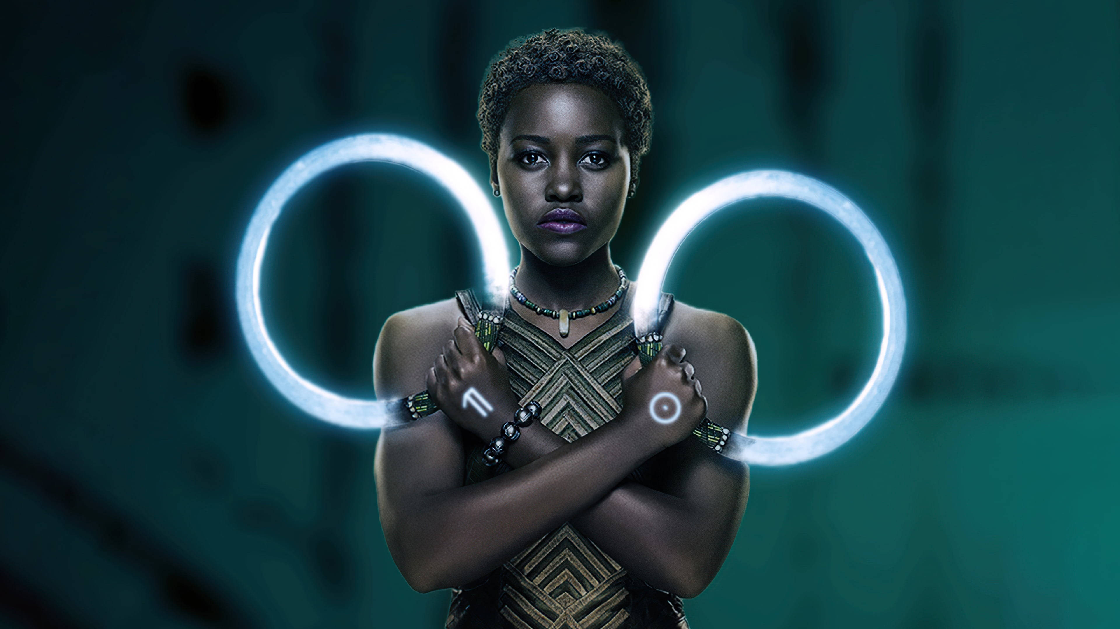 Wakanda 桌布 壁紙 — 一位短捲髮的優雅女性，在深藍綠色背景前，將發光的藍色環圈抱在胸前。