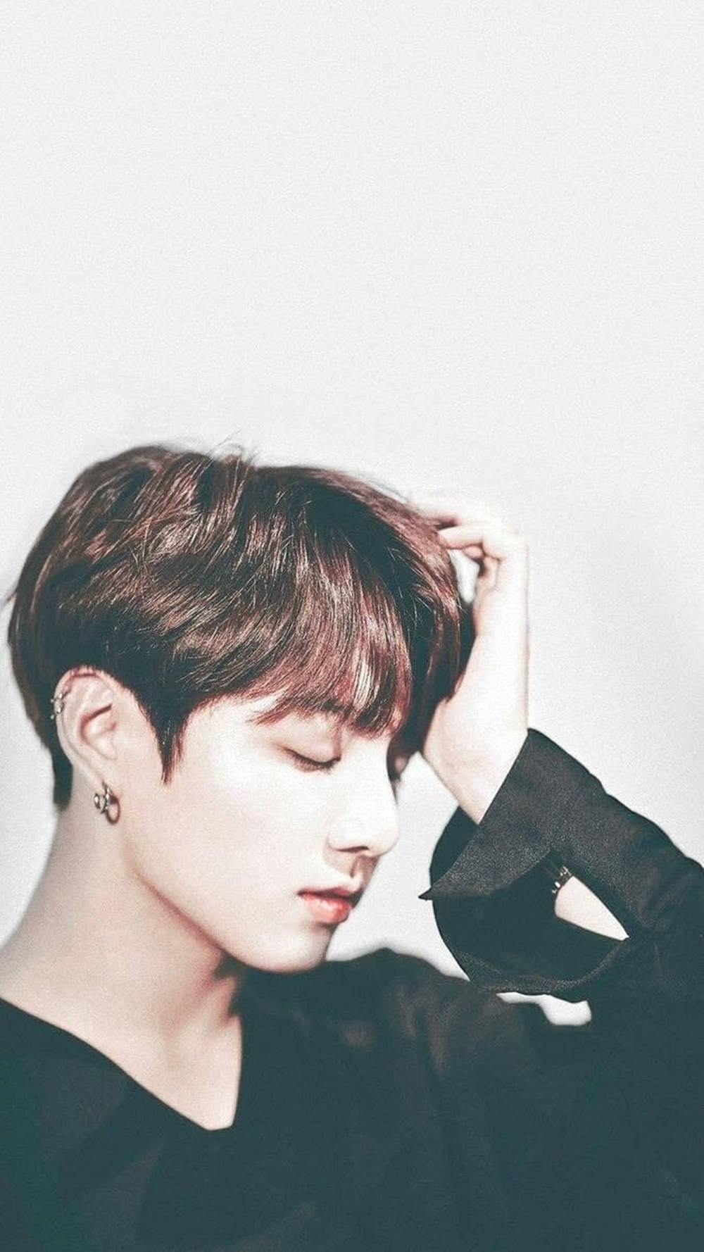 BTS 桌布 壁紙 — 一位短棕髮、閉著眼睛的年輕男子，輕輕地將頭靠在一片純白背景上。