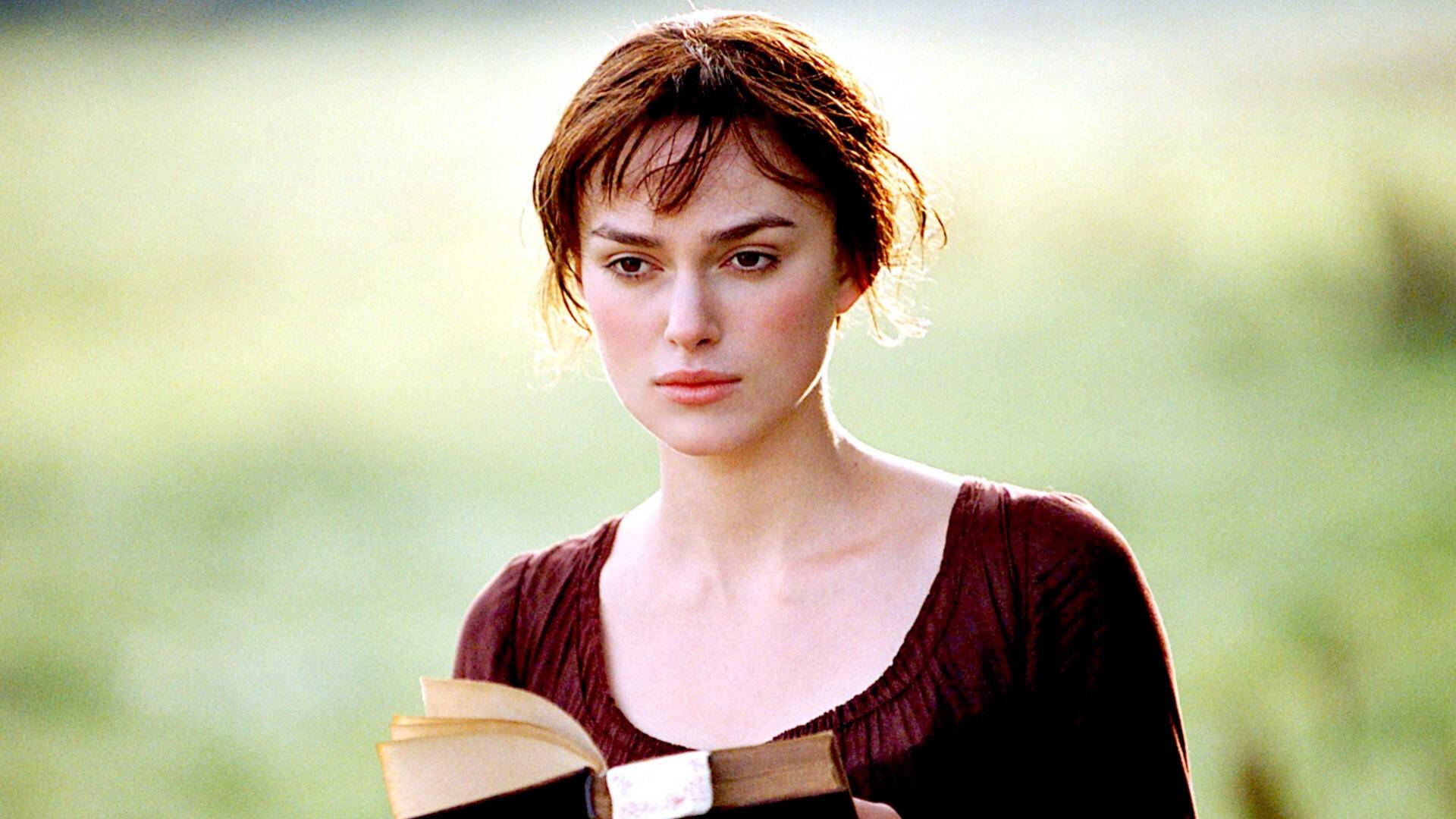 Pride And Prejudice 桌布 壁紙 — 一位短棕髮女性手持一本打開的書，背景是柔和的綠色田野。