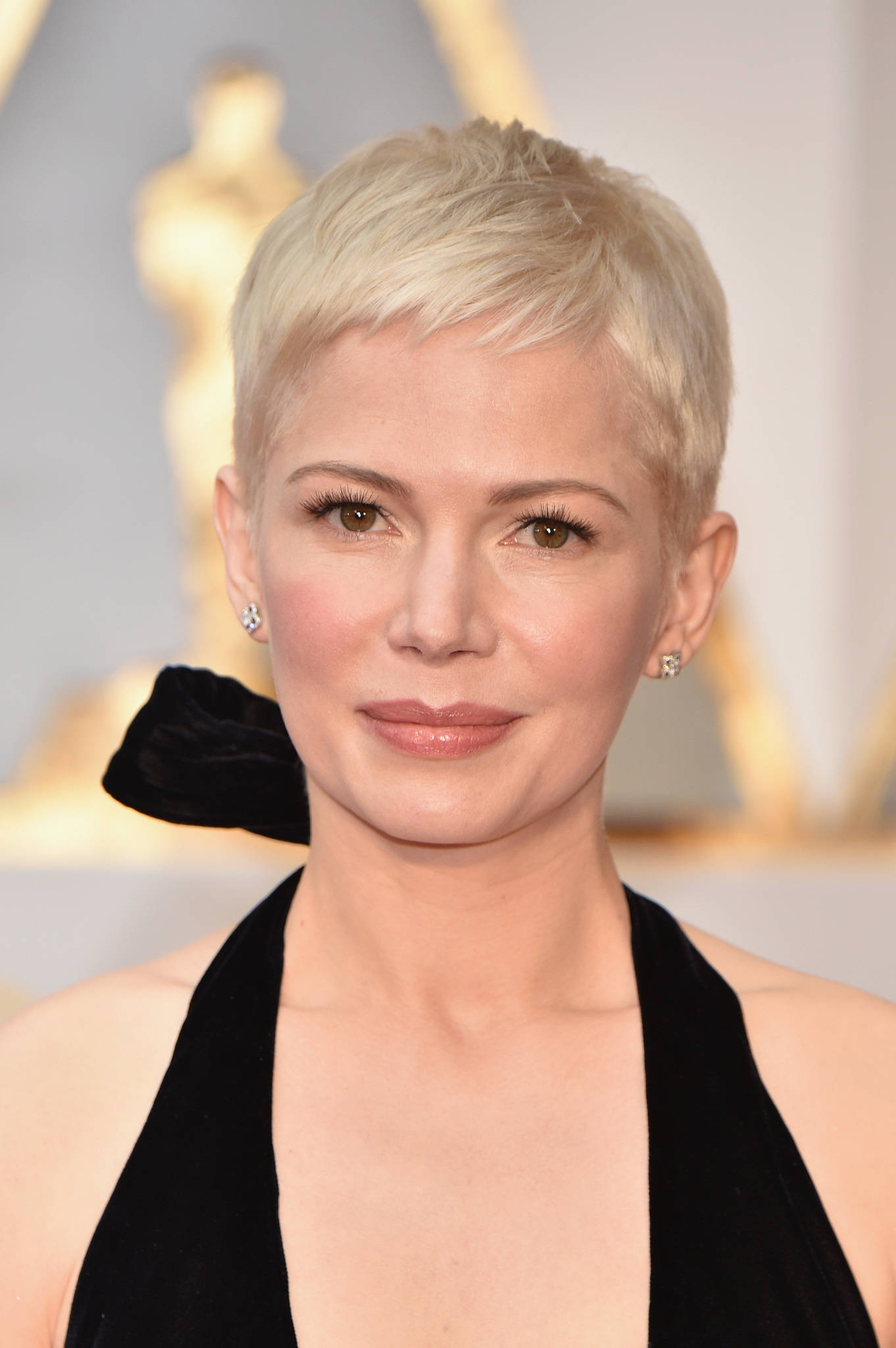 Celebrity 桌布 壁紙 — 一位短白金髮女性在頒獎典禮上穿著黑色天鵝絨掛頸連衣裙和鑽石耳環的特寫肖像。