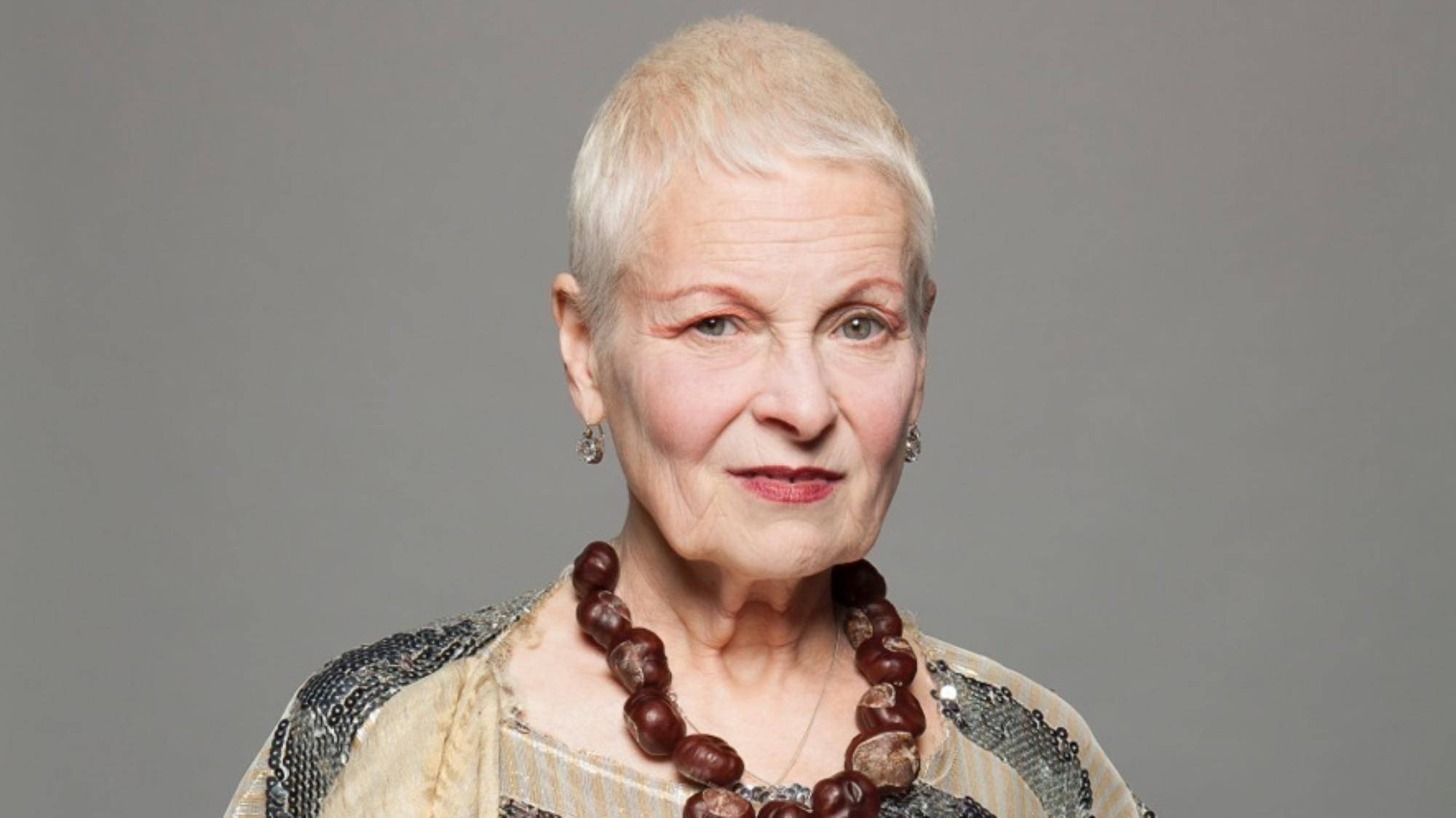 Vivienne Westwood 桌布 壁紙 — 一位短白髮的老年女士，戴著珠鏈和亮片上衣，背景是純灰色。