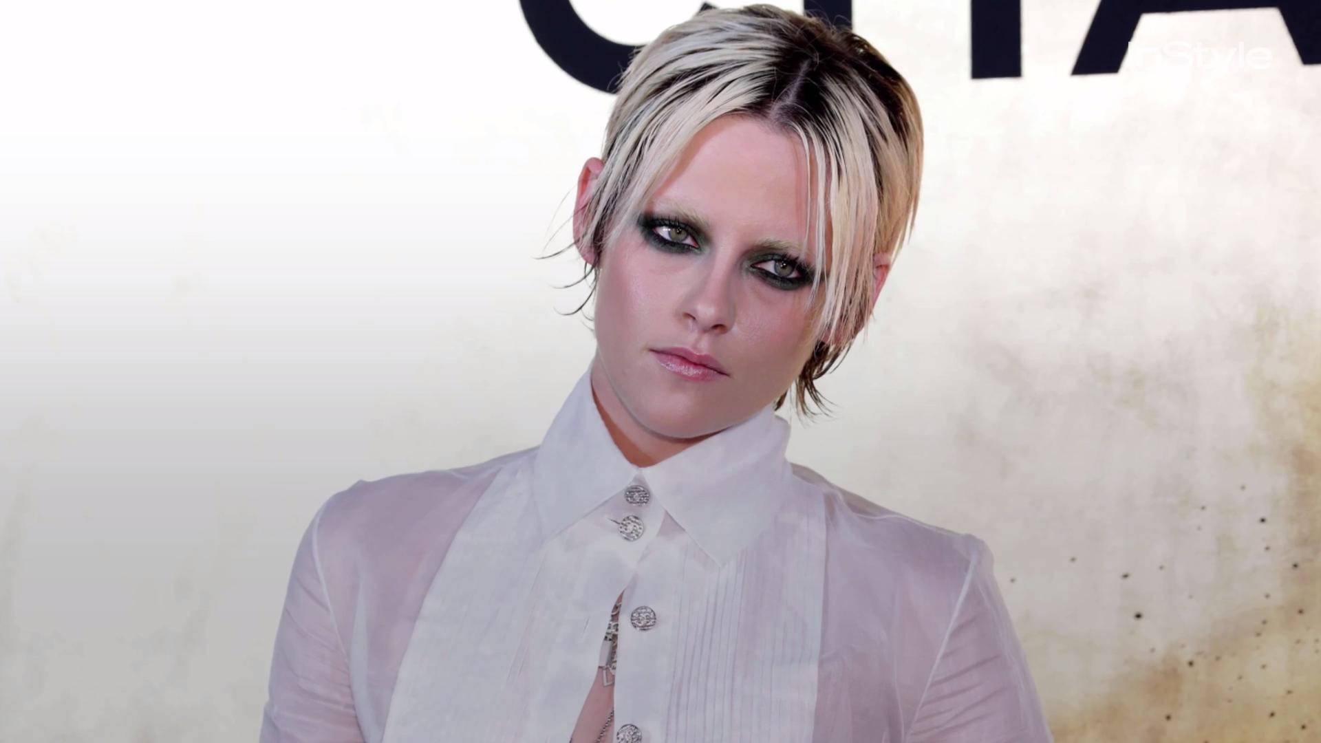 Kristen 桌布 壁紙 — 一位短金髮、化著戲劇性深色眼妝的女性，穿著透明白色襯衫，專注地凝視鏡頭。
