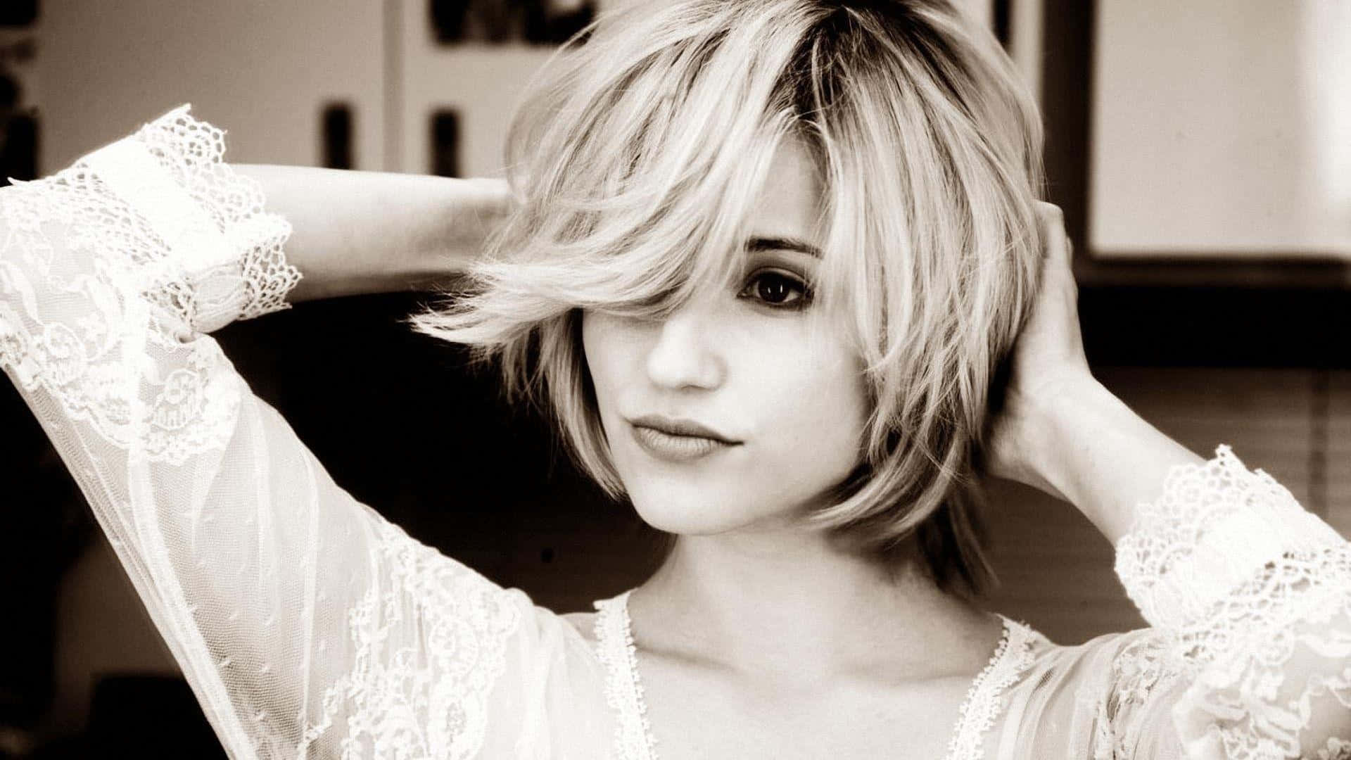 dianna agron 桌布 壁紙 — 一位短金髮、穿著蕾絲袖子的女性，在柔和的棕褐色調肖像中輕輕觸摸她的頭髮。