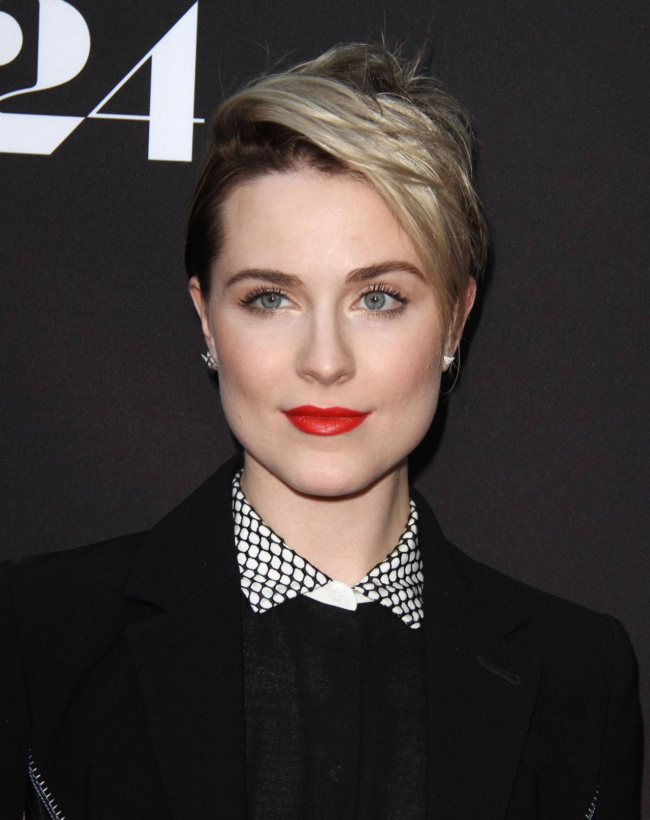 Celebrity 桌布 壁紙 — 一位短金髮、紅唇大膽的優雅女性，在深色背景下穿著黑色西裝外套，內搭圖案領口。