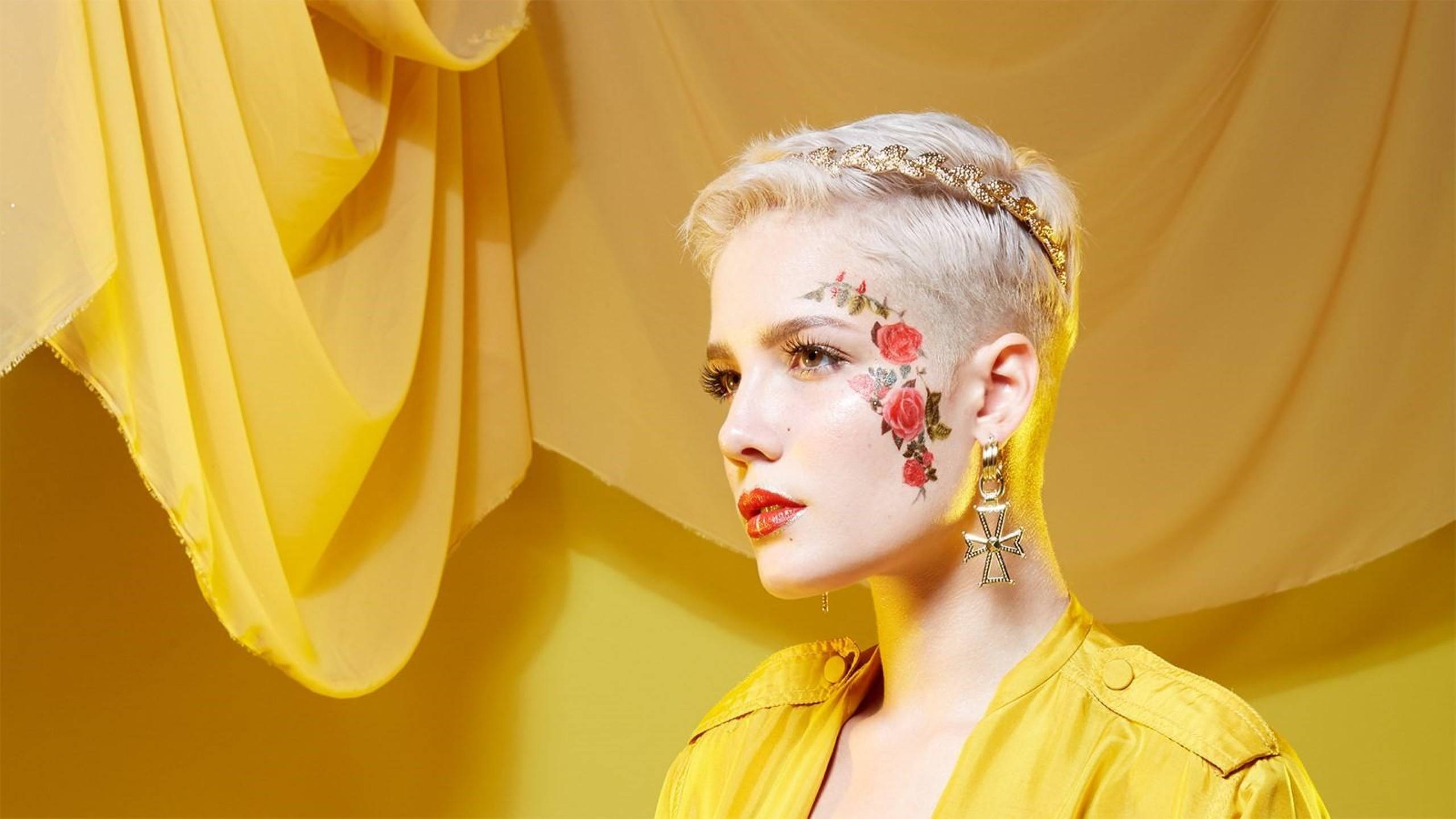Halsey 桌布 壁紙 — 一位短金髮、臉上有花卉彩繪的女性，在金色垂簾背景下若有所思地凝視。