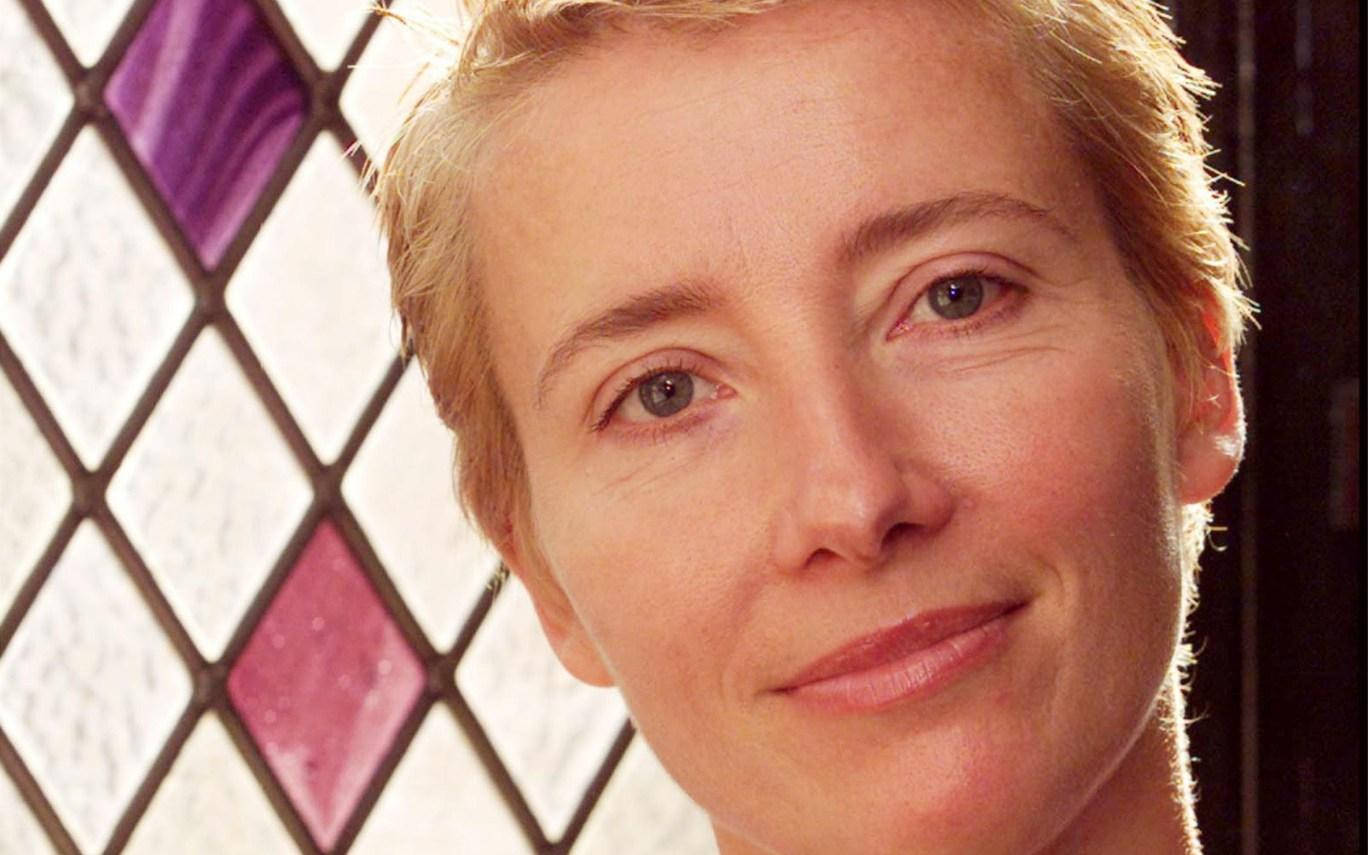 emma thompson 桌布 壁紙 — 一位短金髮女性在菱形圖案、紫色和白色玻璃的彩繪玻璃窗前微笑的特寫肖像。