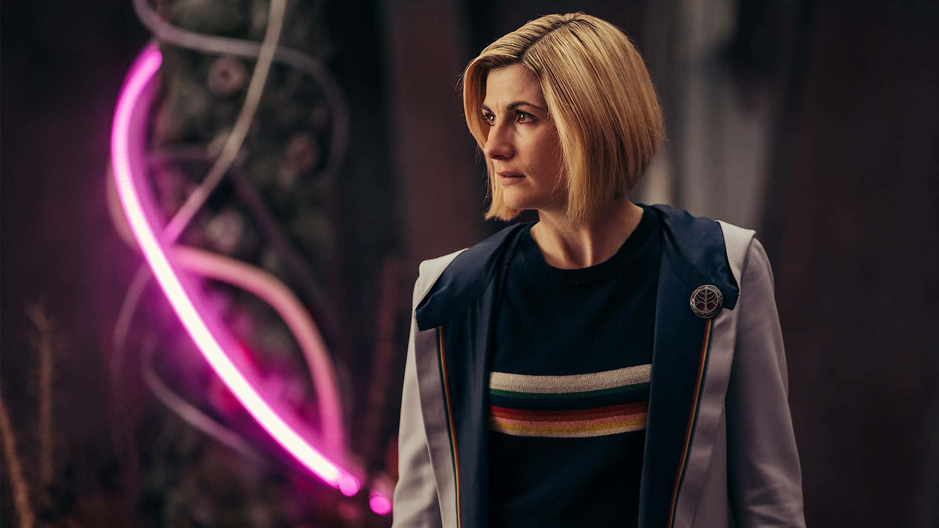 Doctor Who HD 桌布 壁紙 — 一位短金髮女性站在昏暗的空間中，被身後發光的粉紅色霓虹螺旋照亮。