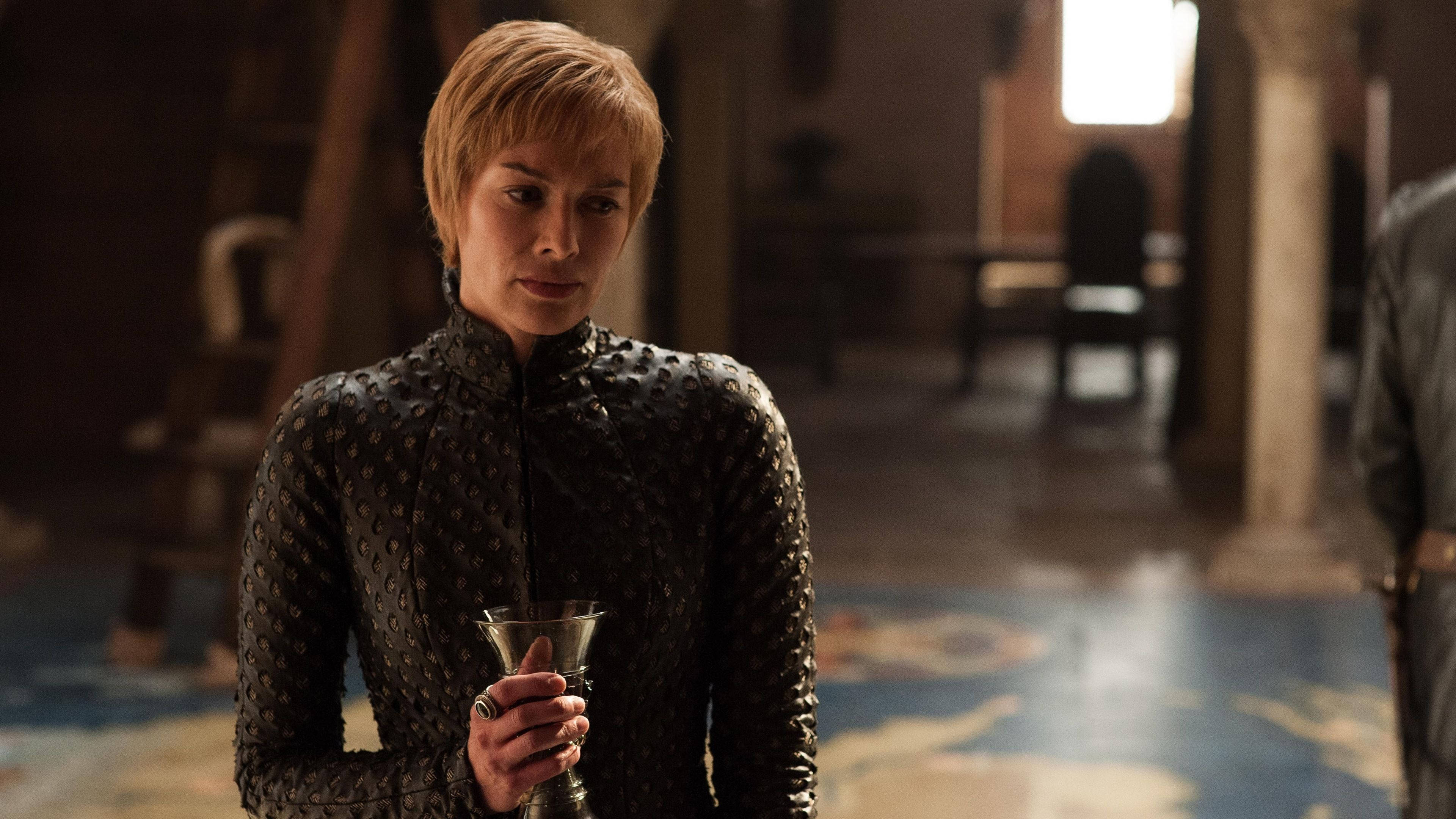 cersei lannister 桌布 壁紙 — 一位短金髮女性身穿深色鱗甲束腰外衣，在光線昏暗、地板有圖案的石廳中手持高腳杯。