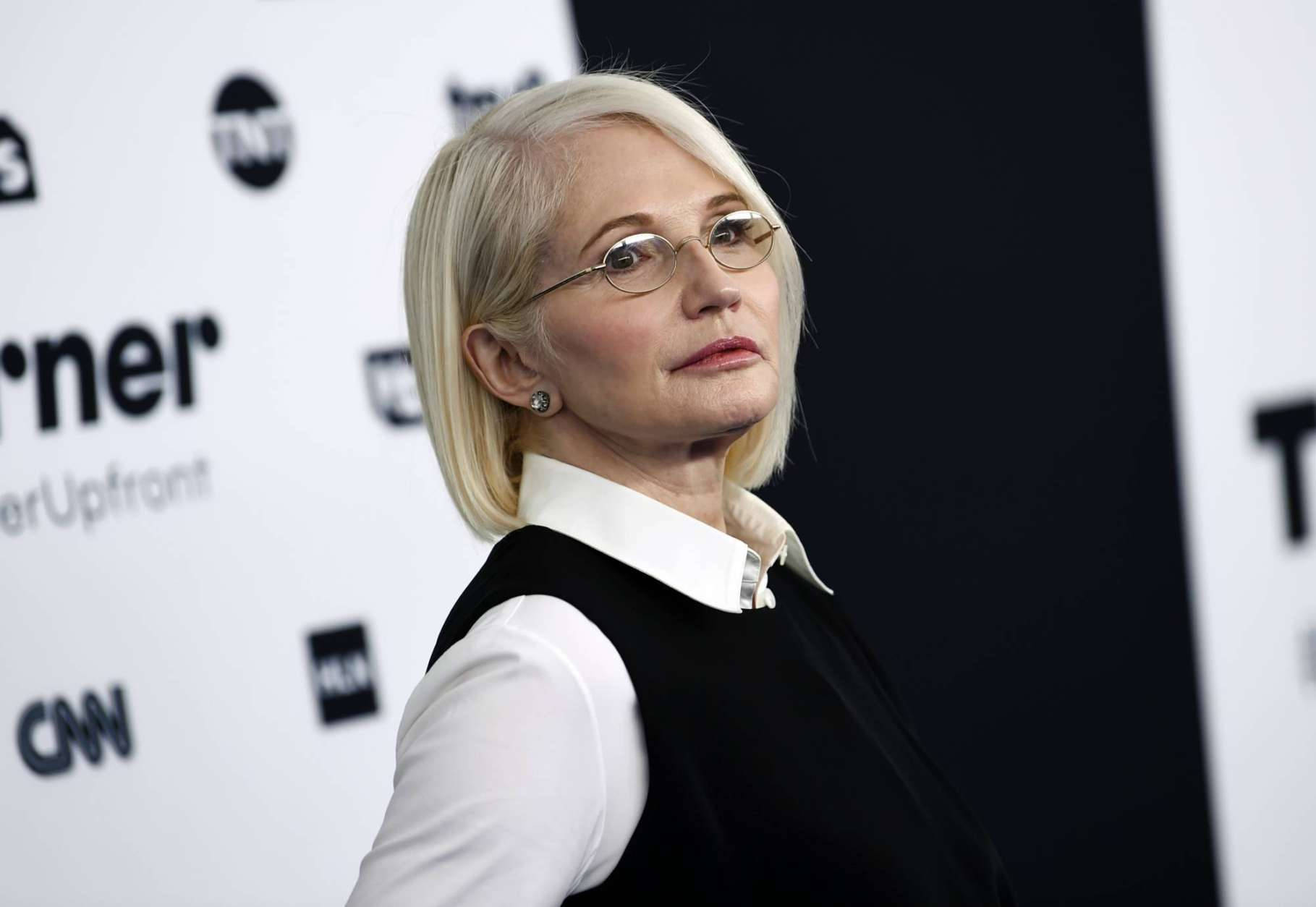 Celebrity 桌布 壁紙 — 一位短金髮戴眼鏡的女性在背景有標誌的媒體活動中望向旁邊。