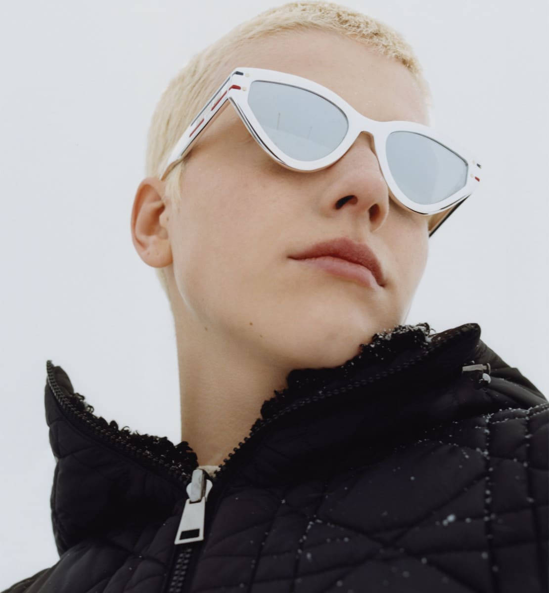 戴白色太陽眼鏡和黑色冬季外套的人站在雪中。 — Dior 動態 壁紙