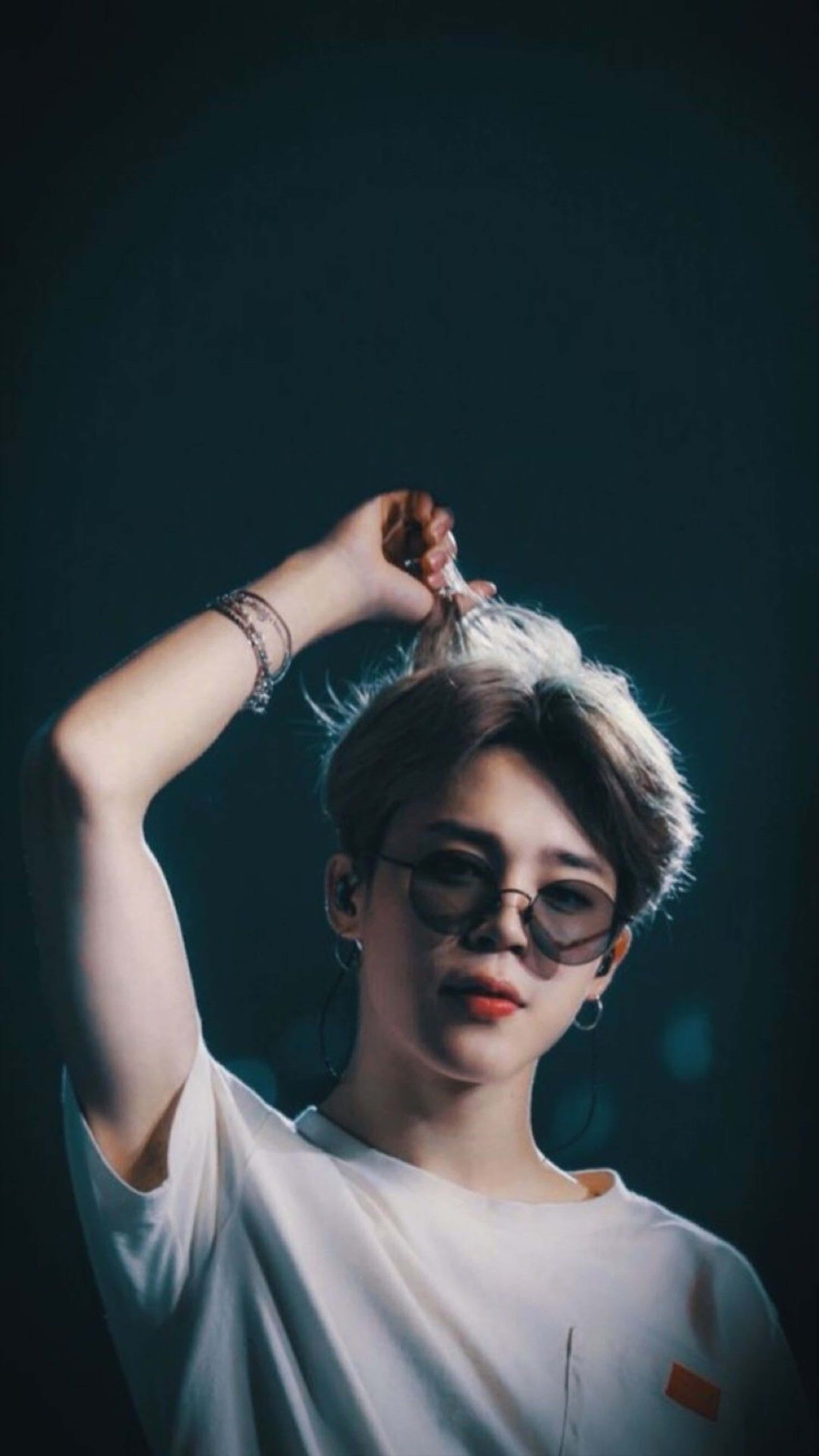 BTS 桌布 壁紙 — 一位短髮戴眼鏡的年輕男子在戲劇性的昏暗燈光下撩起一縷頭髮。