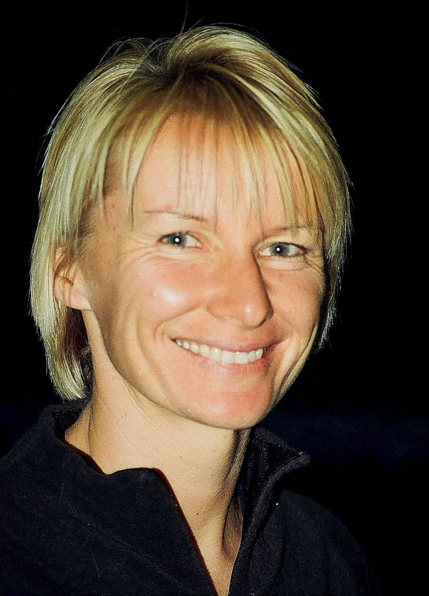 Athlete 桌布 壁紙 — 一位短髮金髮微笑女性的特寫肖像，背景為黑色。