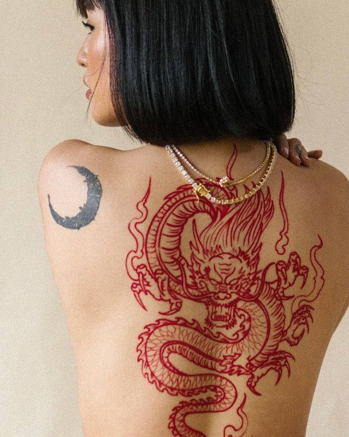 Japanese Dragon Tattoo 桌布 壁紙 — 一位短黑髮女性展示覆蓋她背部的醒目紅色龍紋身和肩上的新月紋身。