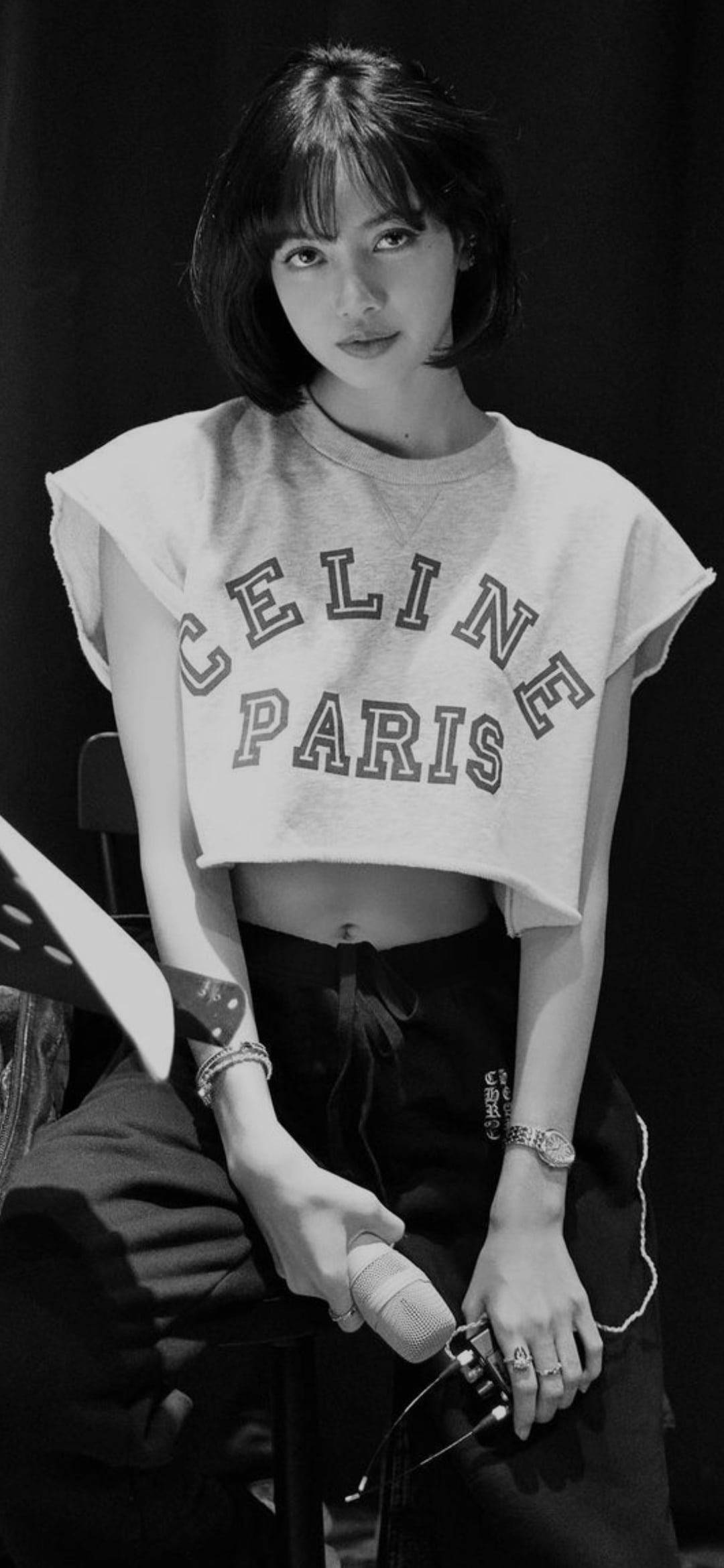 lisa 桌布 壁紙 — 一位短黑髮的年輕女性穿著Celine Paris短版衛衣，在黑色背景前手持麥克風。