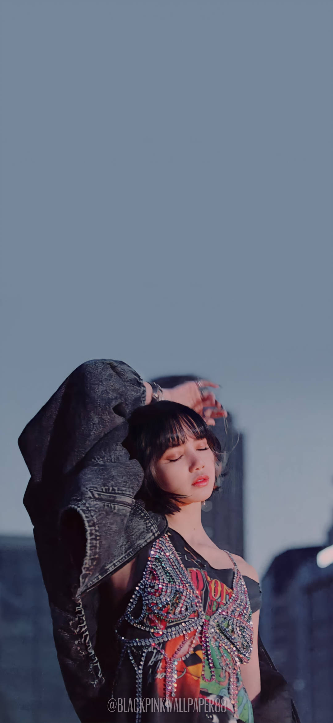 Lalisa 桌布 壁紙 — 一位短黑髮的年輕女性站在朦朧的藍天下，穿著鑲有寶石的上衣，肩上披著一件牛仔外套。
