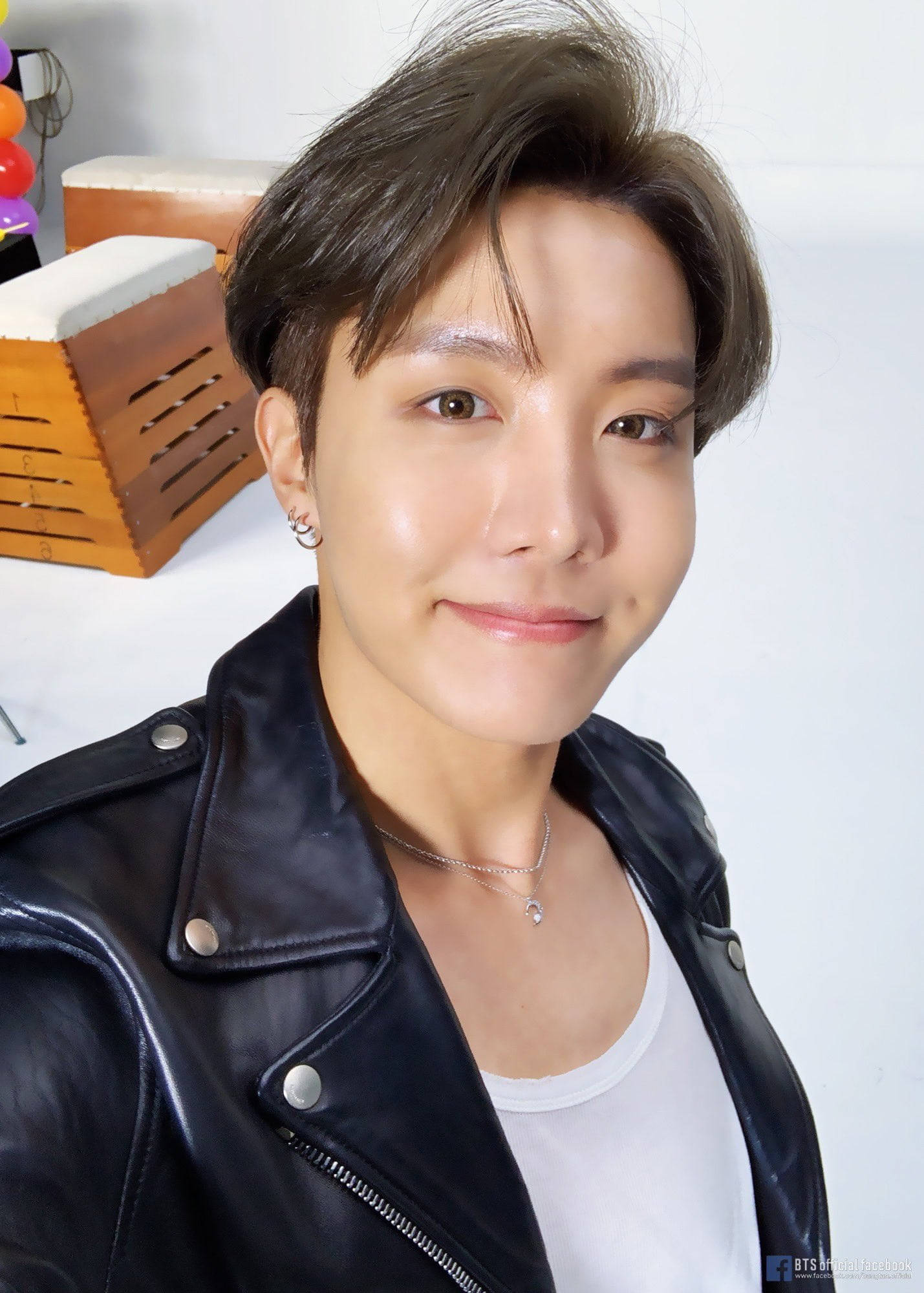 jhope 桌布 壁紙 — 一位短黑髮的年輕男子穿著黑色皮夾克內搭白色T恤，溫柔地微笑。
