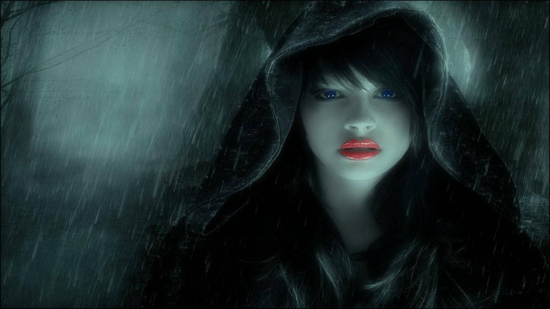 女孩 桌布 壁紙 — 一位神秘女子身穿深色連帽斗篷，站在暴風雨浸濕的場景中，擁有發光的藍色眼睛和鮮紅的嘴唇。