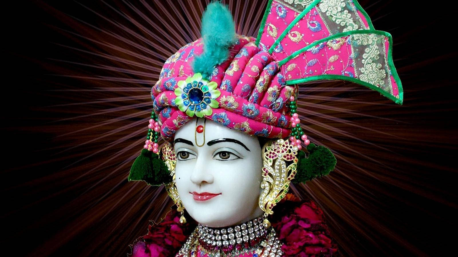 Swaminarayan 桌布 壁紙 — 一位神聖人物身穿鮮豔的粉紅色和金色服飾，背後迸發出耀眼的光芒。
