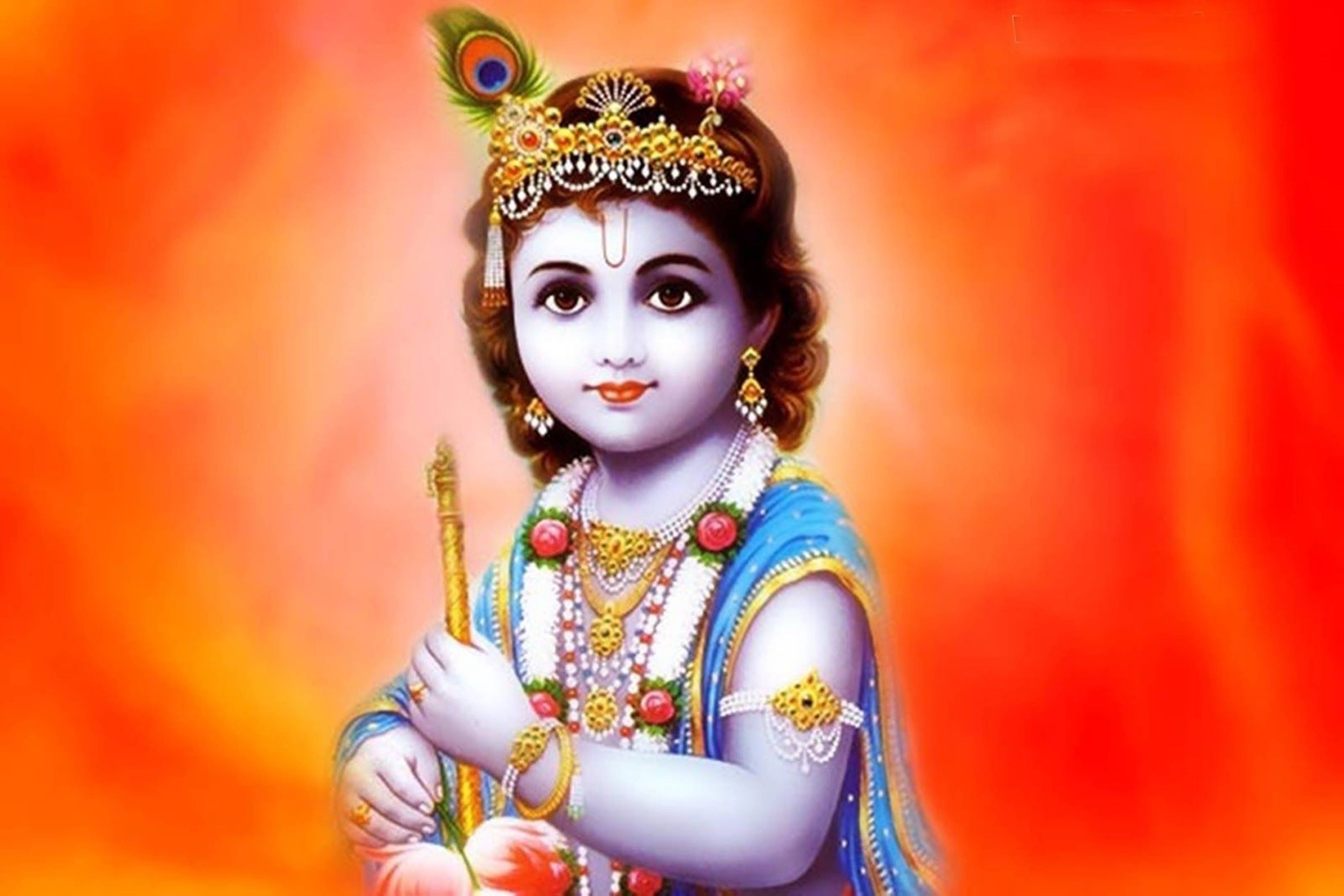 krishna god 桌布 壁紙 — 一位神聖的兒童神祇，佩戴金色珠寶和藍色服飾，手持權杖，背景是耀眼的橙色和紅色漸變。