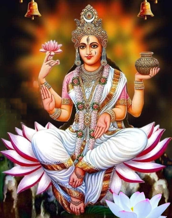 Lakshmi Devi 桌布 壁紙 — 一位神聖的印度教女神安詳地坐在粉紅蓮花上，手持蓮花和聖壺，背景溫暖發光。