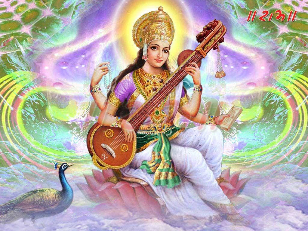 Saraswati Devi 桌布 壁紙 — 一位神聖的女神，頭戴金色皇冠，身穿紫色服飾，優雅地坐在粉紅色的蓮花上，彈奏弦樂器，背景是旋轉的宇宙，附近有一隻孔雀。