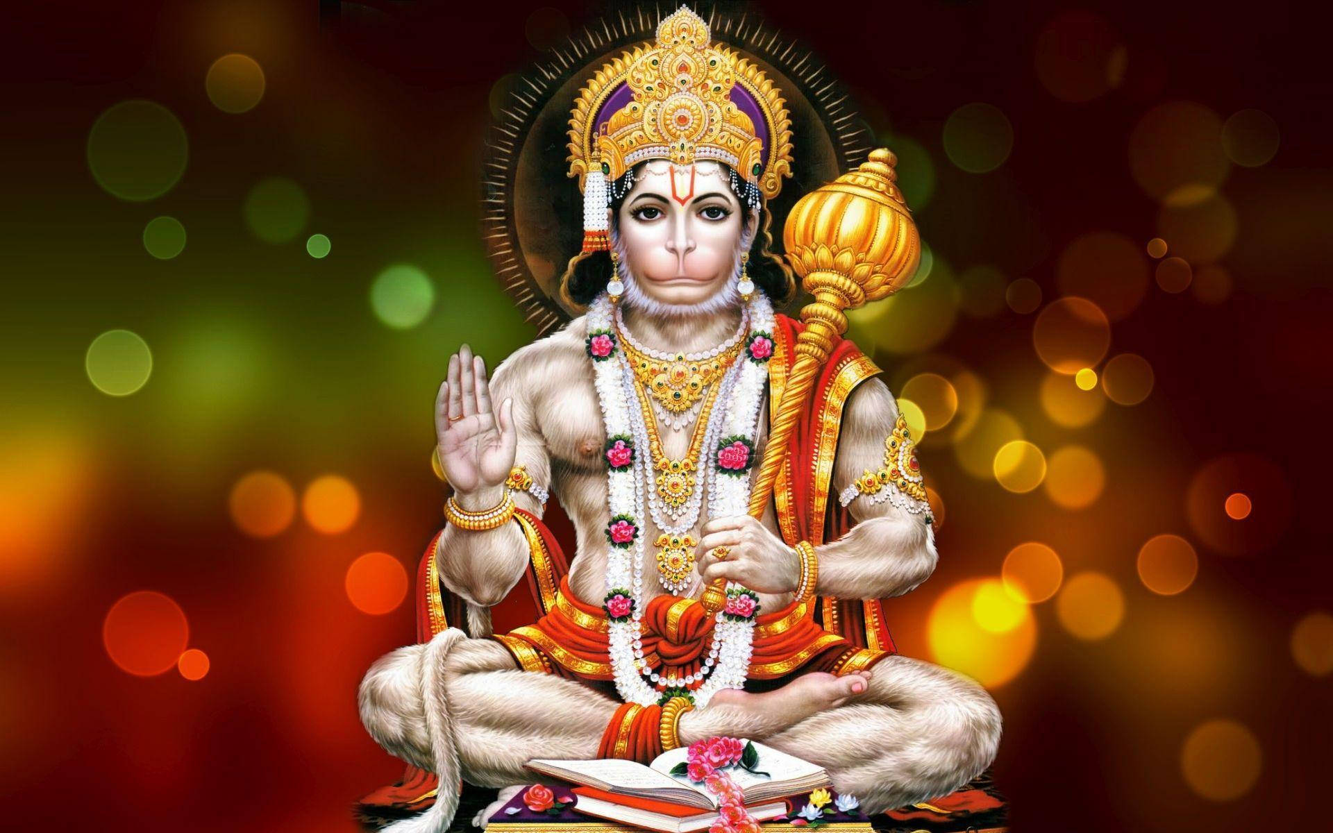 Hanuman 桌布 壁紙 — 一位神聖的猴神，佩戴金色珠寶，身穿紅橙色長袍，安然坐在一本書上，背景是閃爍的散景。