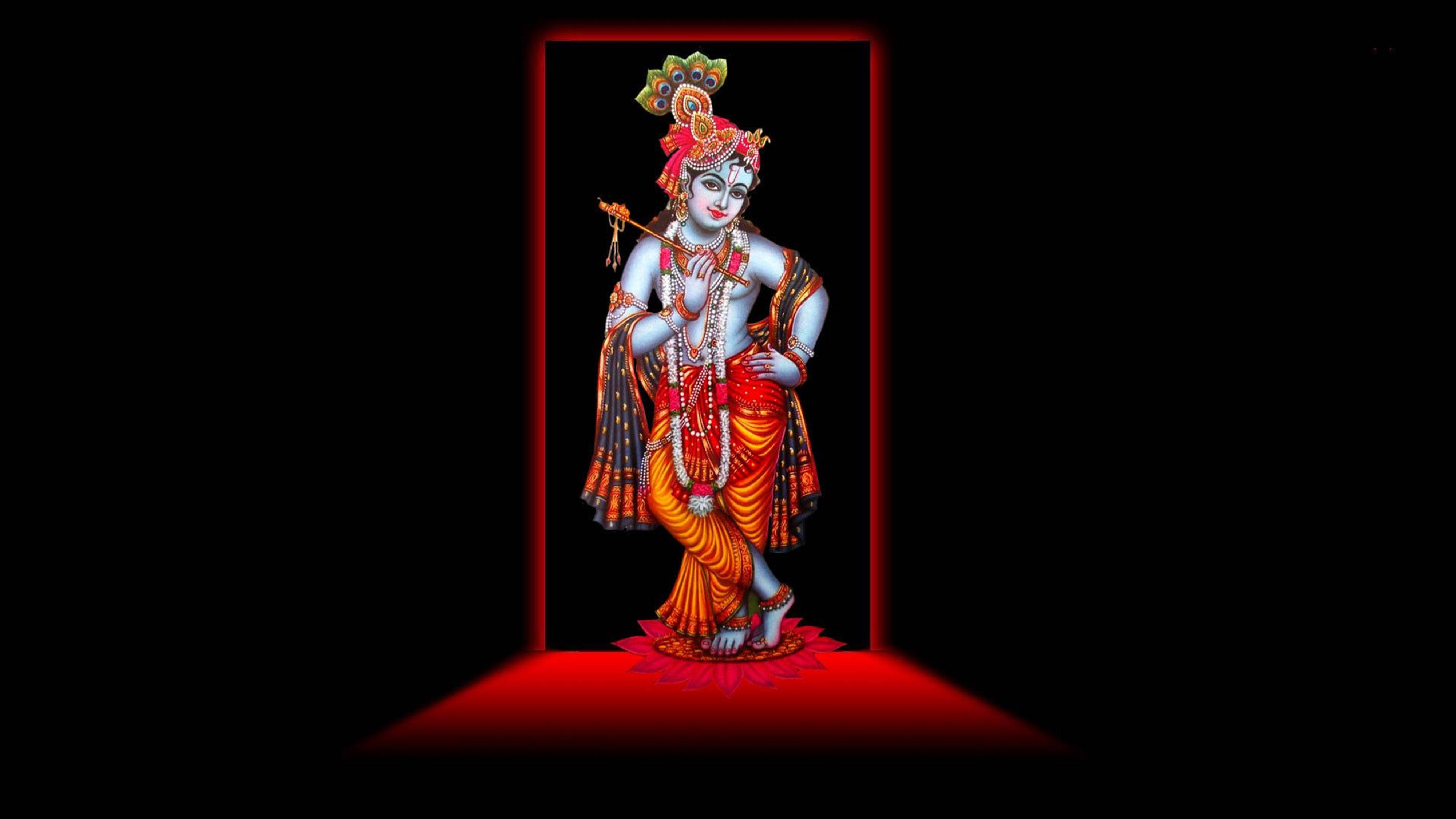 Hindu God 桌布 壁紙 — 一位神聖的藍皮膚神祇，頭戴孔雀冠，手持長笛，站在紅色照亮的門口，背景為黑色。